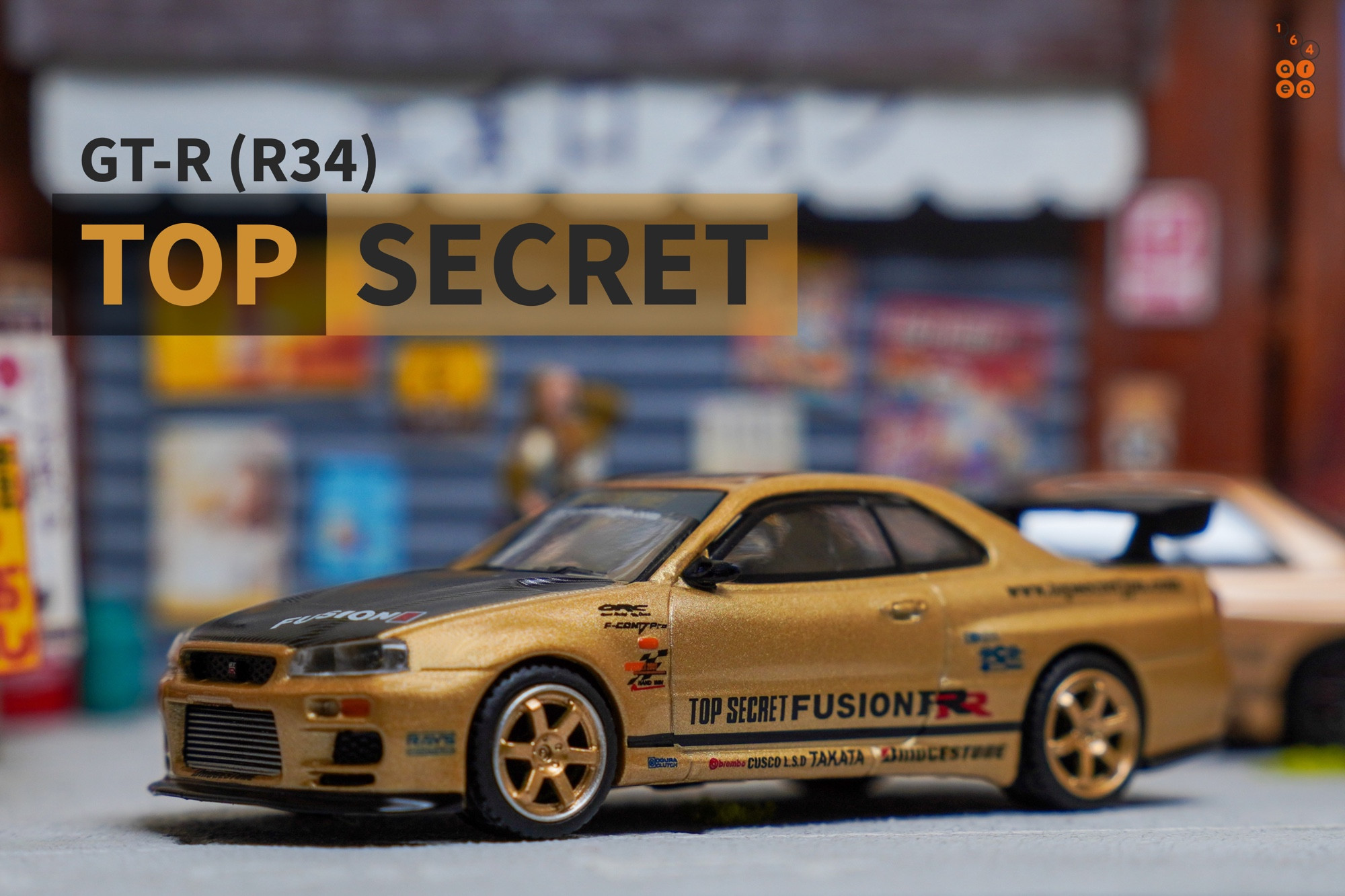 A left side of Nissan Skyline GT-R (R34) Top Secret, Top Secret Gold by MINI GT in 1:64 scale on AREA 164