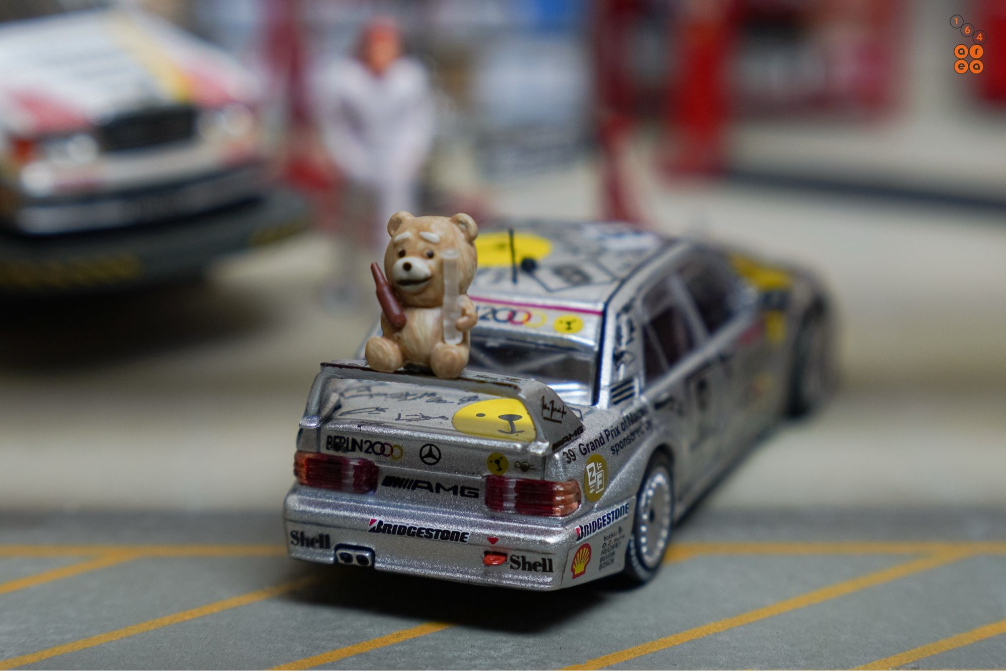 A Ted bear and on a rear wing of Mercedes-Benz 190E 2.5-16 Evolution II, Berlin 2000 livery by Tarmac Works in 1:64 scale with 1:64 figure on AREA 164