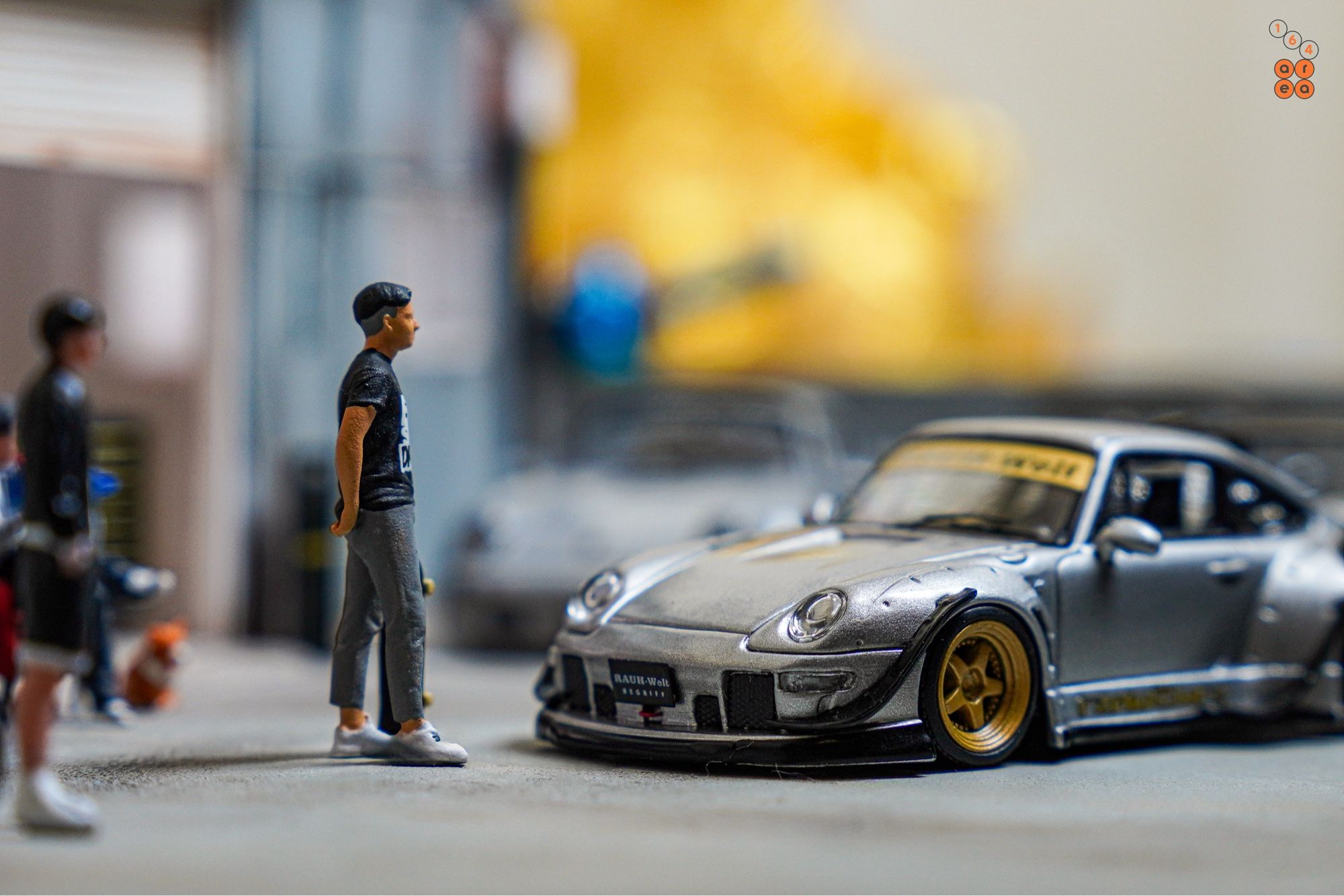 A guy turn to face a Porsche RWB 993 Ram-intra by Street Weapon in 1:64 scale with 1:64 figures on AREA 164