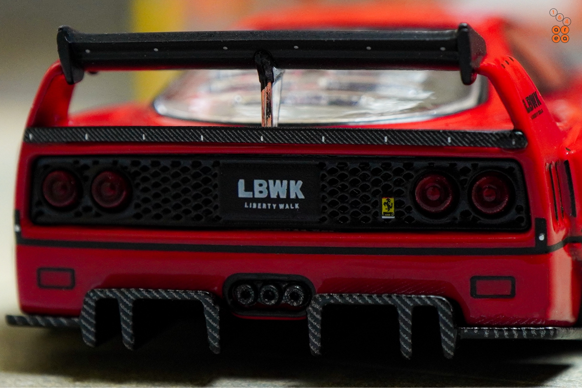 A close-up shot of a red LB-WORKS Ferrari F40 by INNO64 in 1:64 scale on AREA 164