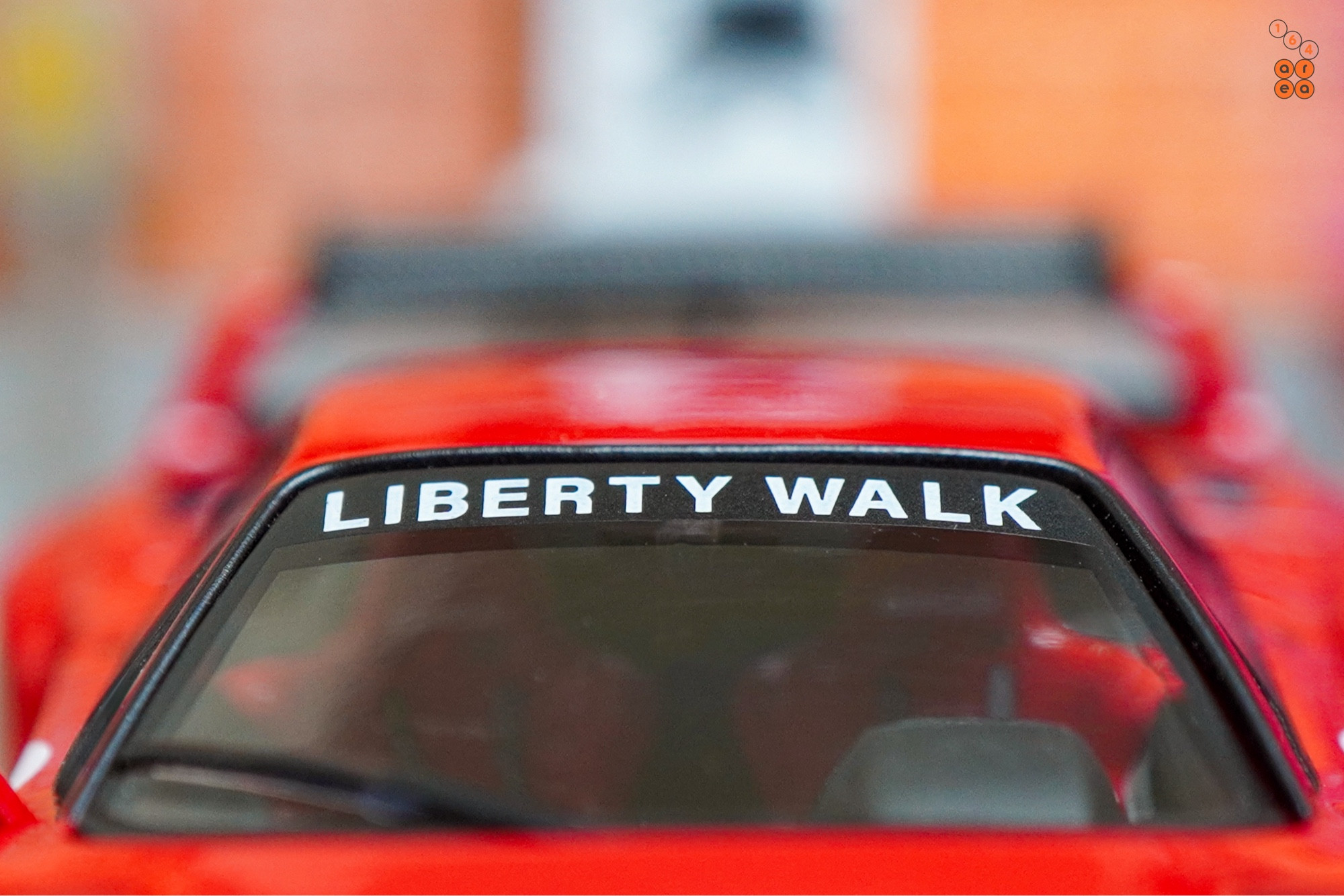 A close-up shot of a red LB-WORKS Ferrari F40 by INNO64 in 1:64 scale on AREA 164