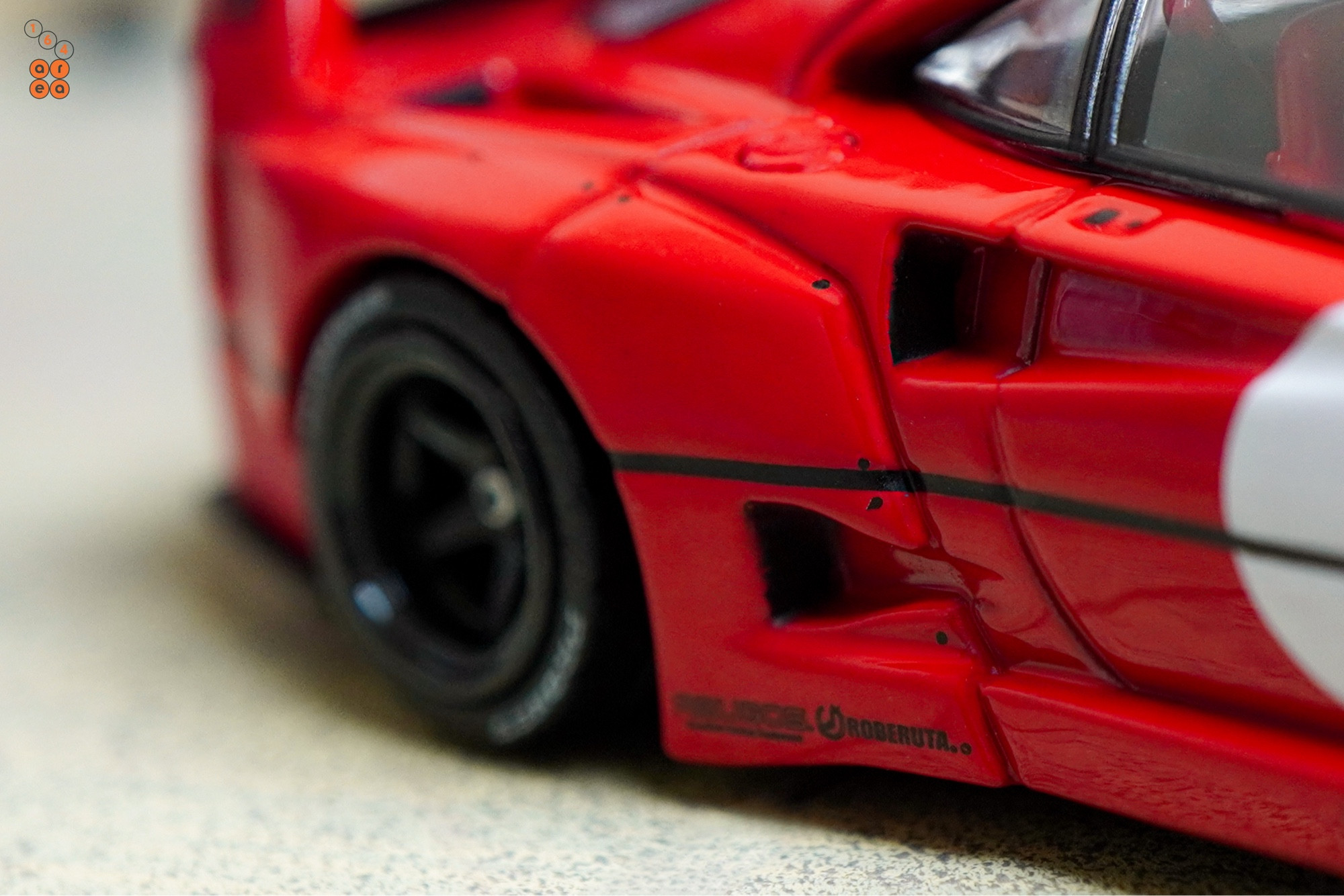 A close-up shot of a red LB-WORKS Ferrari F40 by INNO64 in 1:64 scale on AREA 164