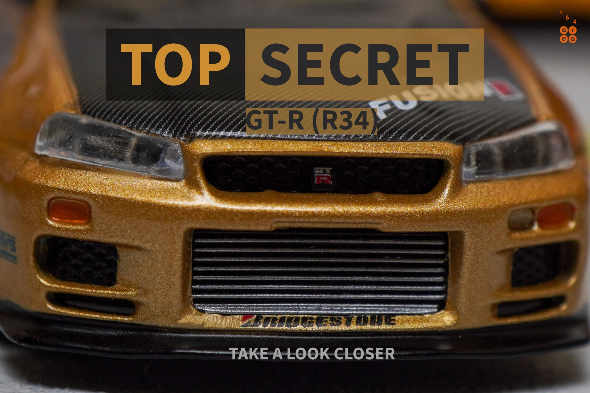 A close-up shot of Nissan Skyline GT-R (R34) Top Secret, Top Secret Gold by MINI GT in 1:64 scale on AREA 164