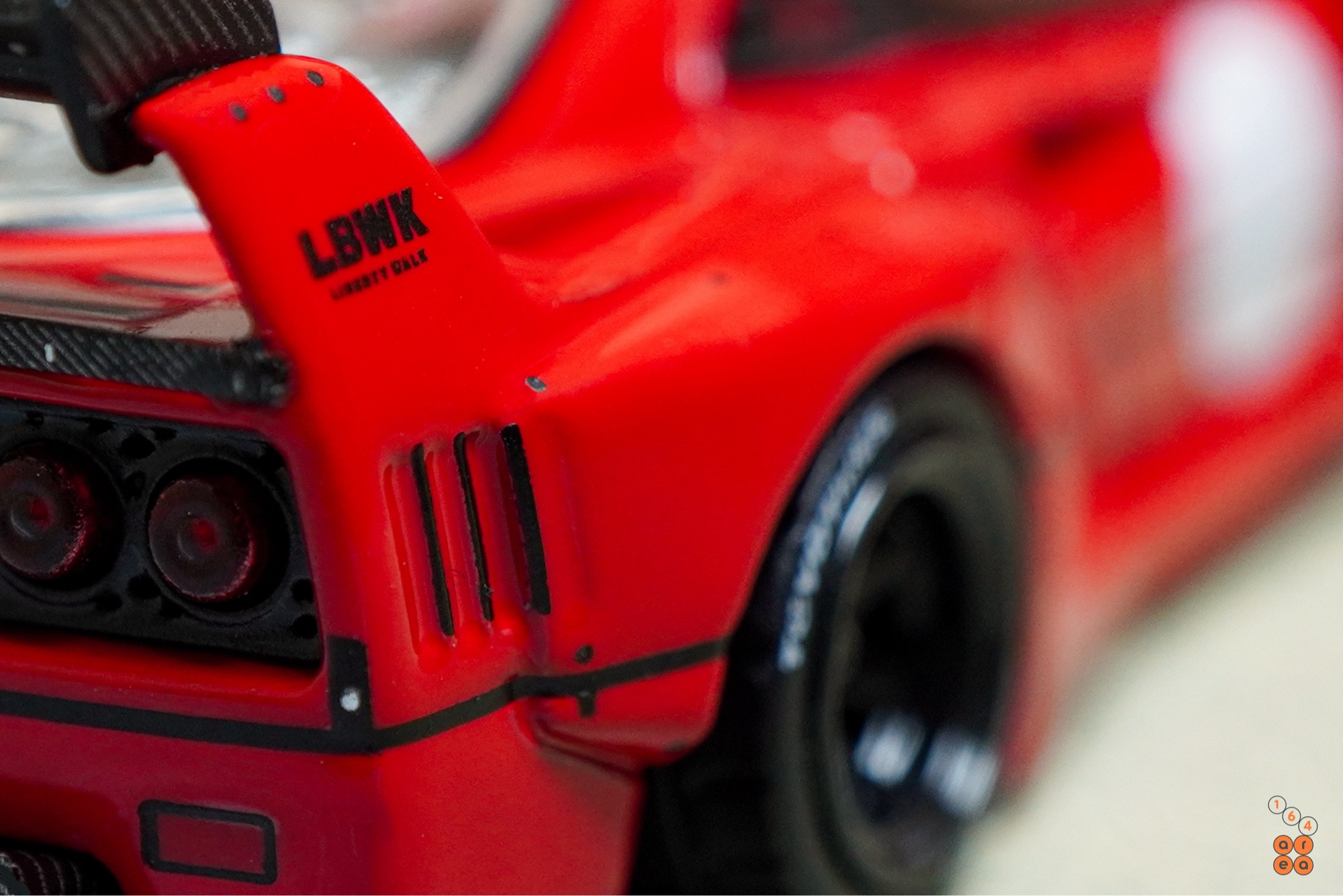 A close-up shot of a red LB-WORKS Ferrari F40 by INNO64 in 1:64 scale on AREA 164