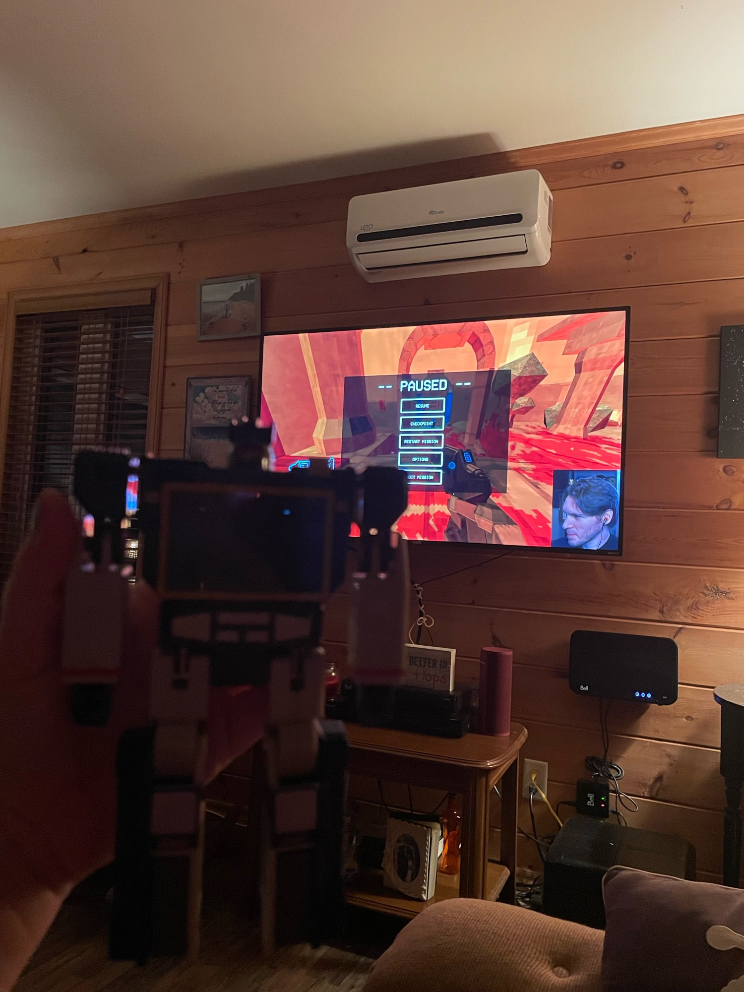 A Soundwave Transformers toy being held up in front of a TV playing Jerma’s stream of ULTRAKILL. The toy is not in focus and is blurry. 