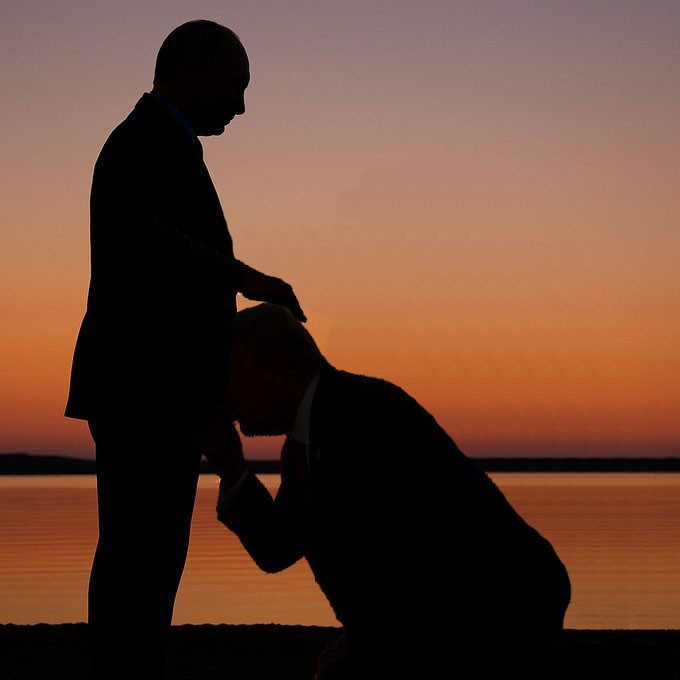 Silhouetted image of two men [Putin and Trump] at sunset. One man is standing (Putin) while the other (Trump) kneels in front of him, appearing to kiss his hand or lower body. The scene is set against a calm body of water with an orange and purple sky in the background.