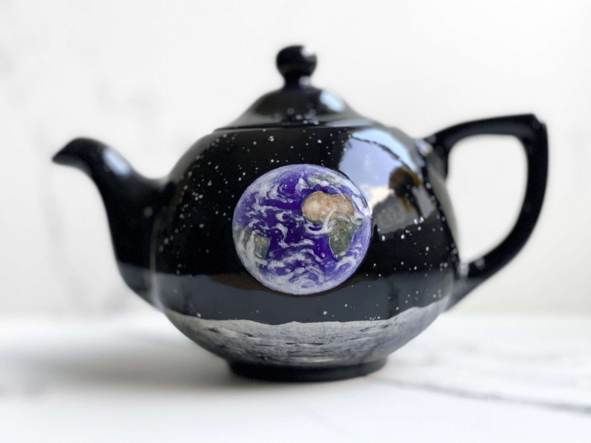 Teapot featuring Earthrise over lunar landscape