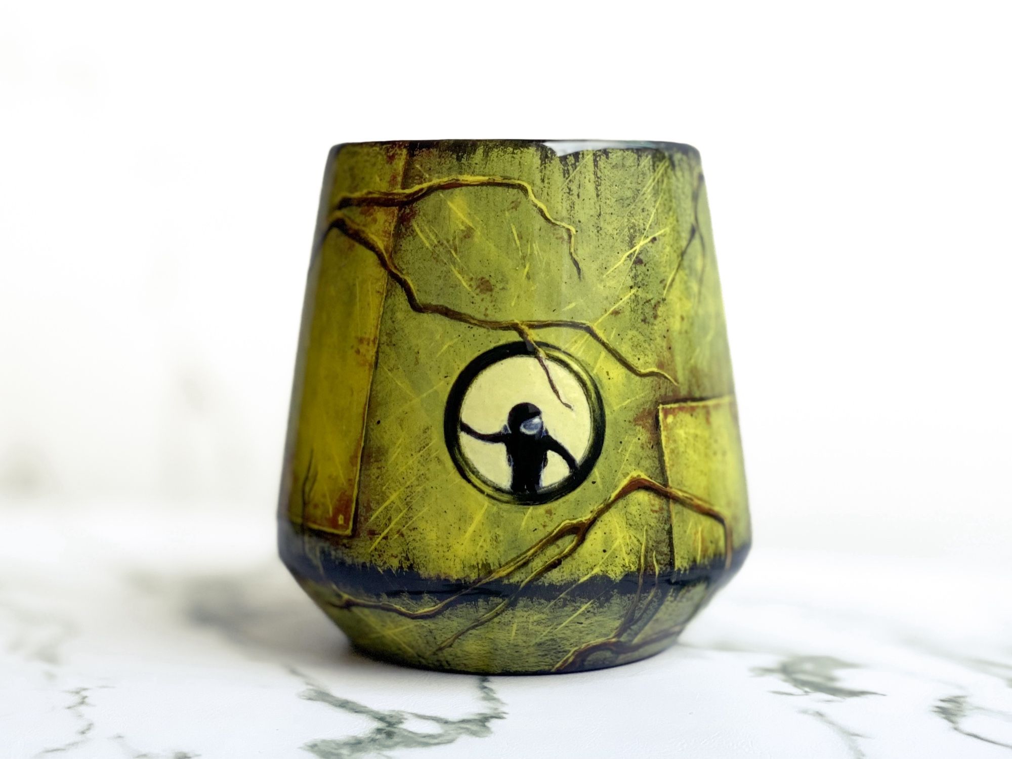 Angled cup featuring weathered green spacecraft. Branches wrap around the outside and an astronaut looks out the round window.