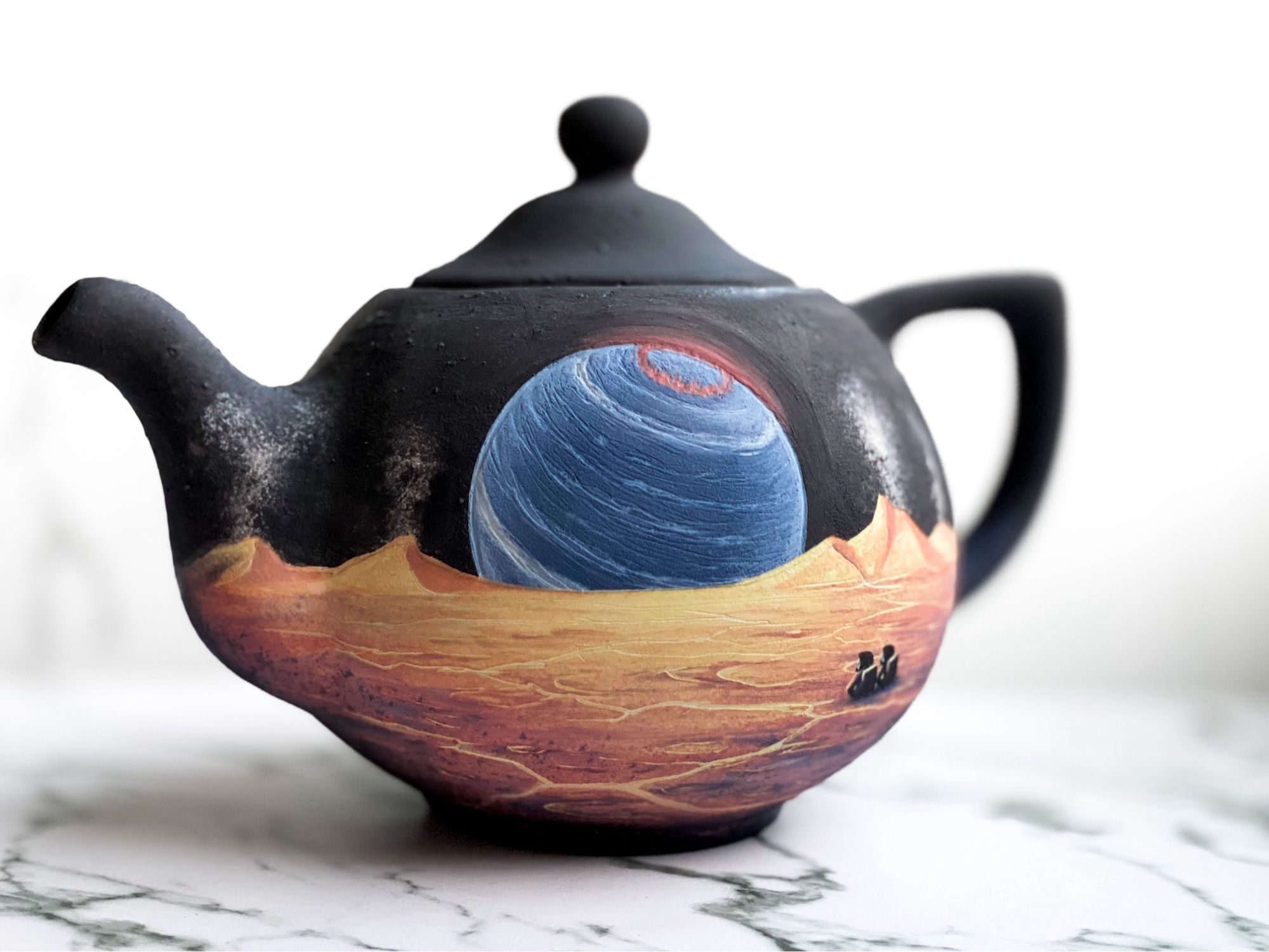 Teapot featuring cracking yellow landscape with erupting volcanoes on the horizon and two astronauts sitting and looking toward a massive blue brown dwarf with a red aurora. (Left)