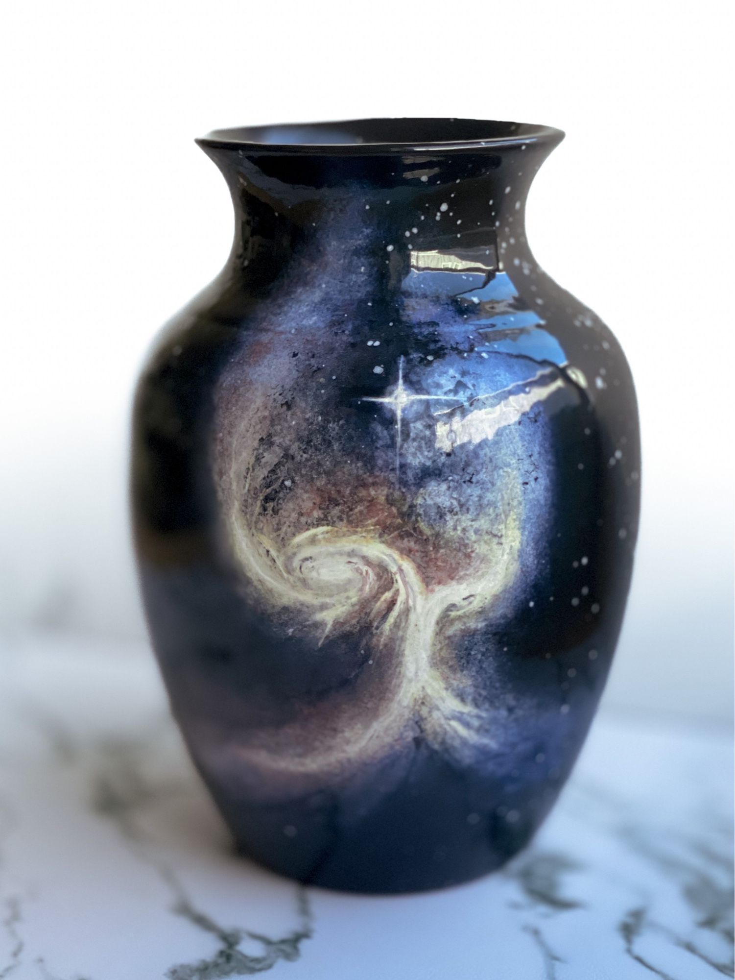 Vase featuring two merging galaxies that unite in a vertical formation resembling a tree or “Angel wing” and one bright star in center.