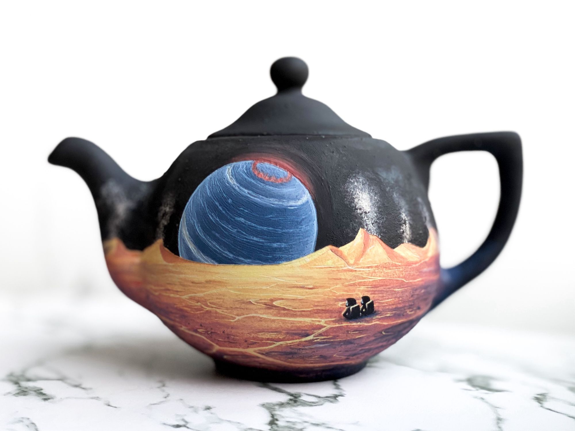 Teapot featuring cracking yellow landscape with erupting volcanoes on the horizon and two astronauts sitting and looking toward a massive blue brown dwarf with a red aurora.