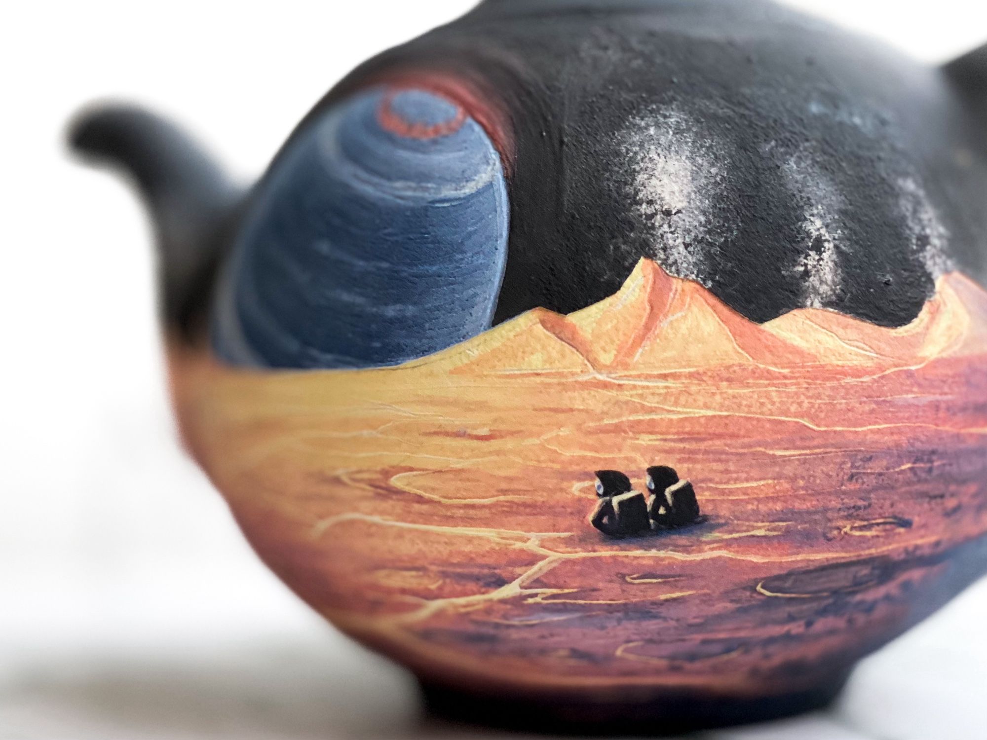 Teapot featuring cracking yellow landscape with erupting volcanoes on the horizon and two astronauts sitting and looking toward a massive blue brown dwarf with a red aurora. (Detail of astronauts)