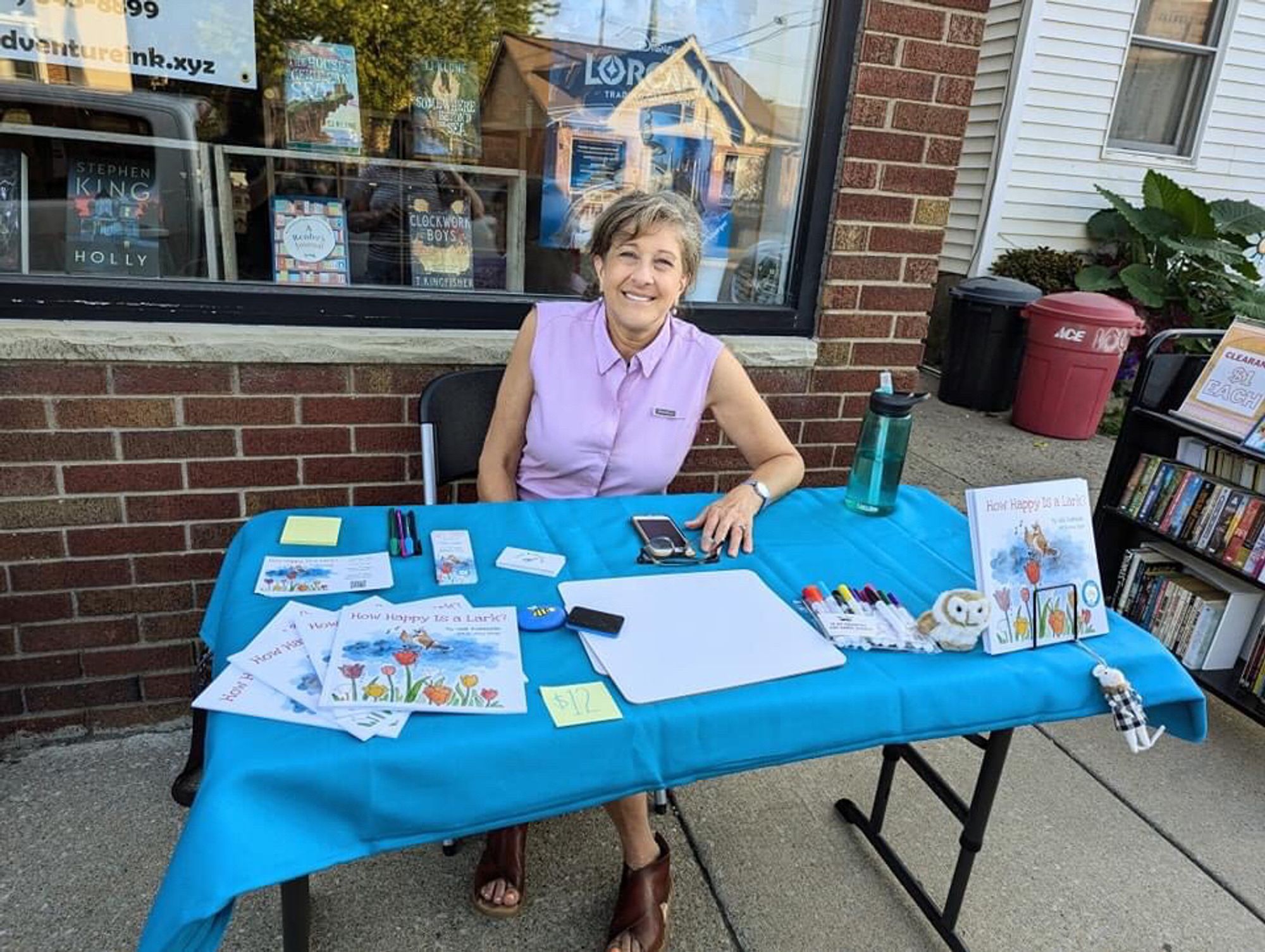 Gail at a table at a recent book event in front of Adventure, Ink