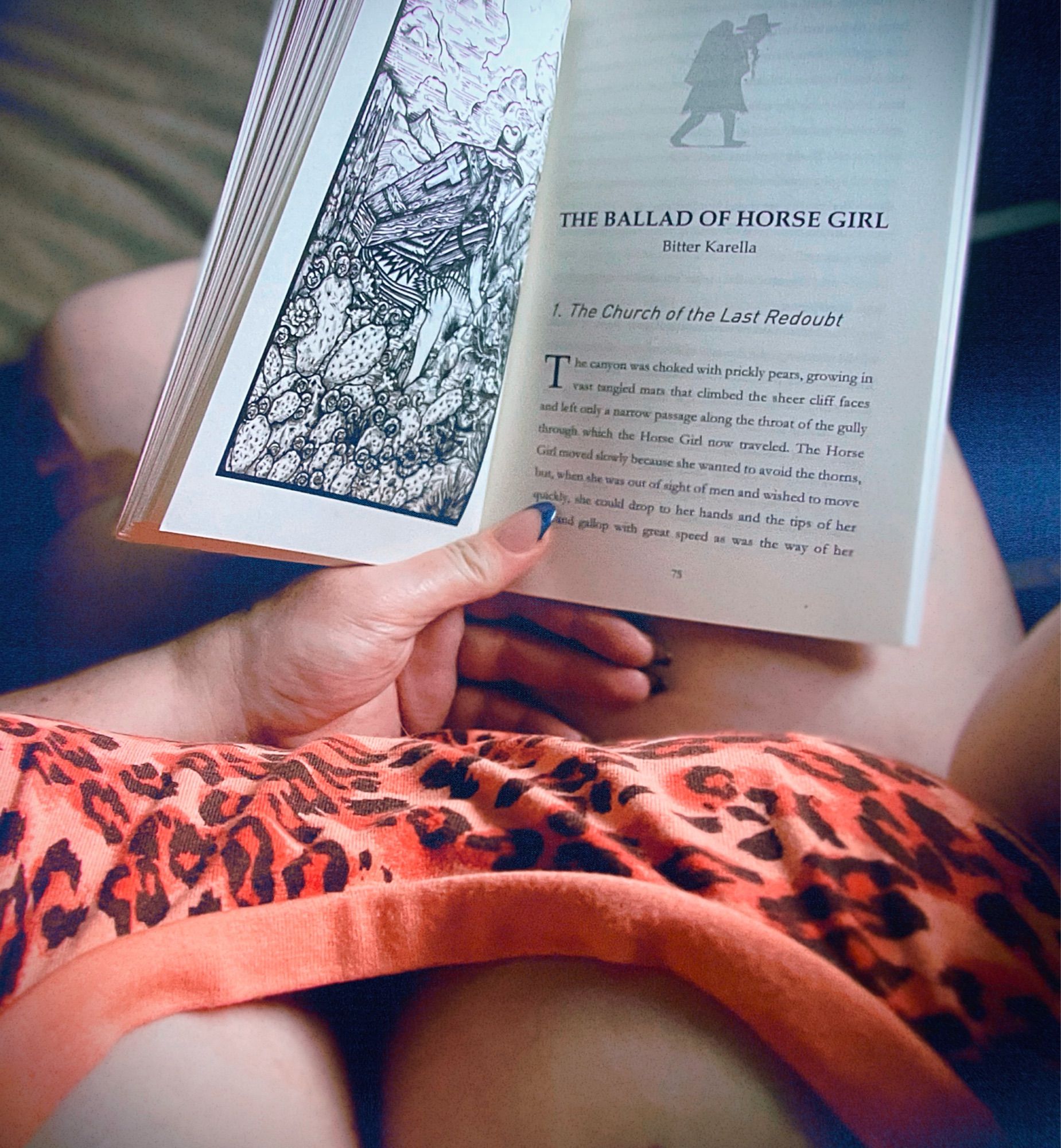 POV photo of me holding The Ballad of Horse Girl novelette open, you can also see down my shirt tee hee