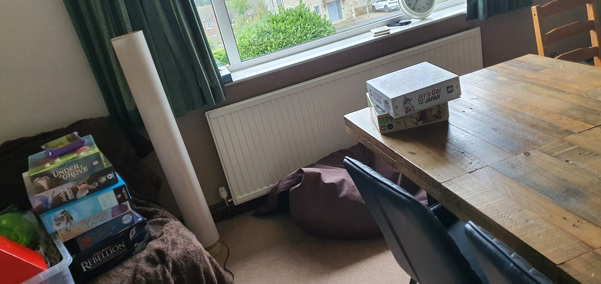 A dining table with two games sitting on it. In the corner of the room there's a lounge chair. Yes, it has a stack of boardgames on it. 