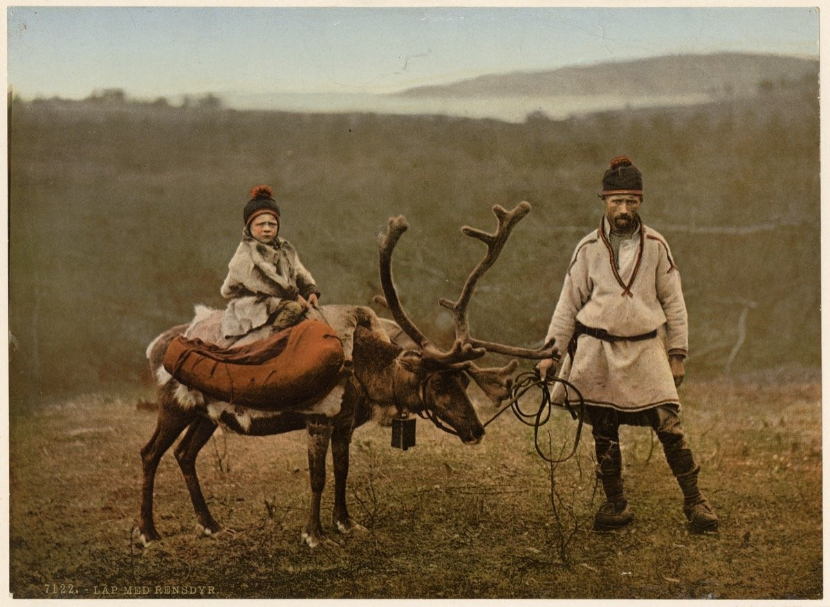 Sámi father and child atop reindeer