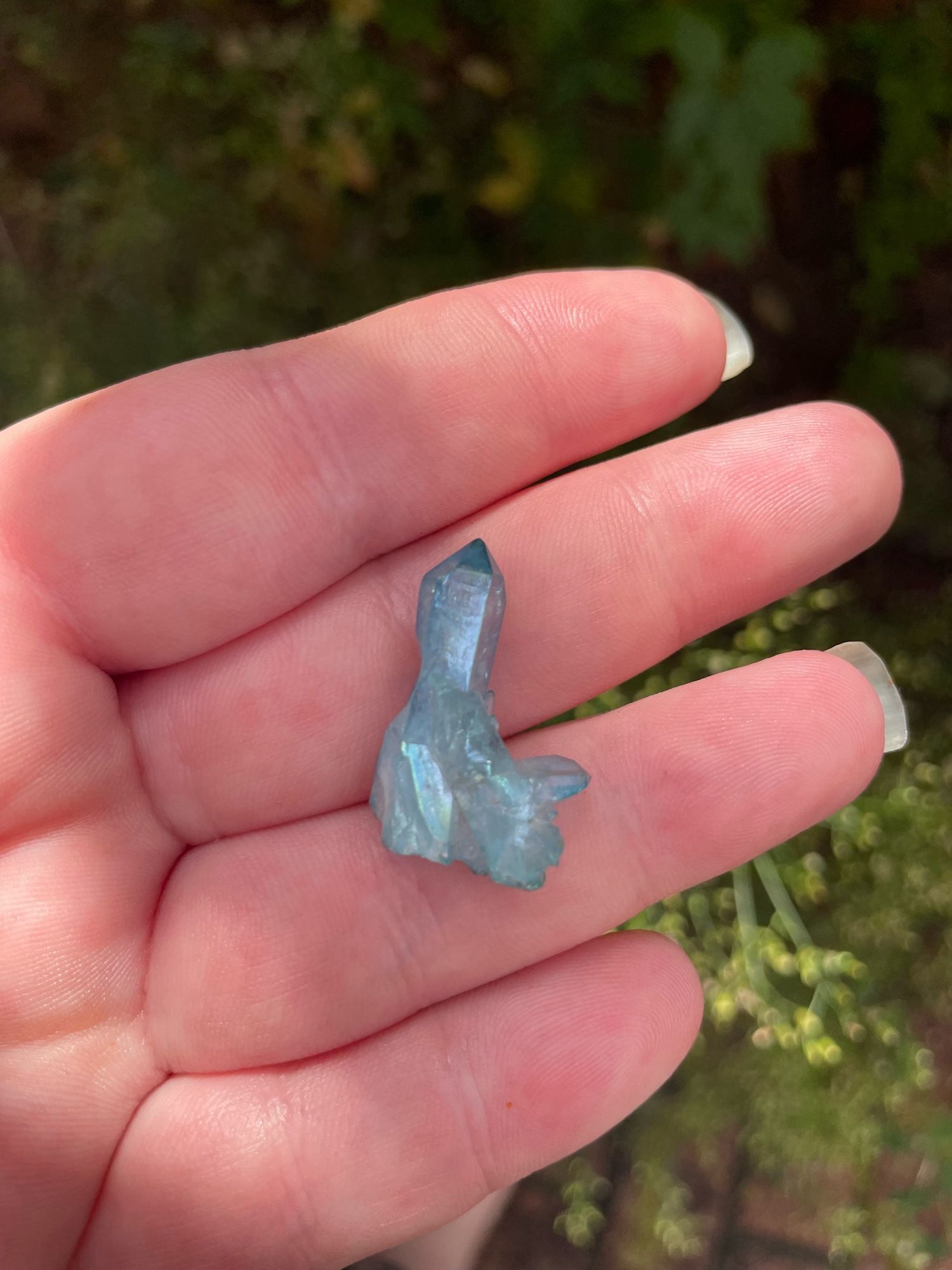 Photo of Kim’s hand holding a small point of angel aura quartz