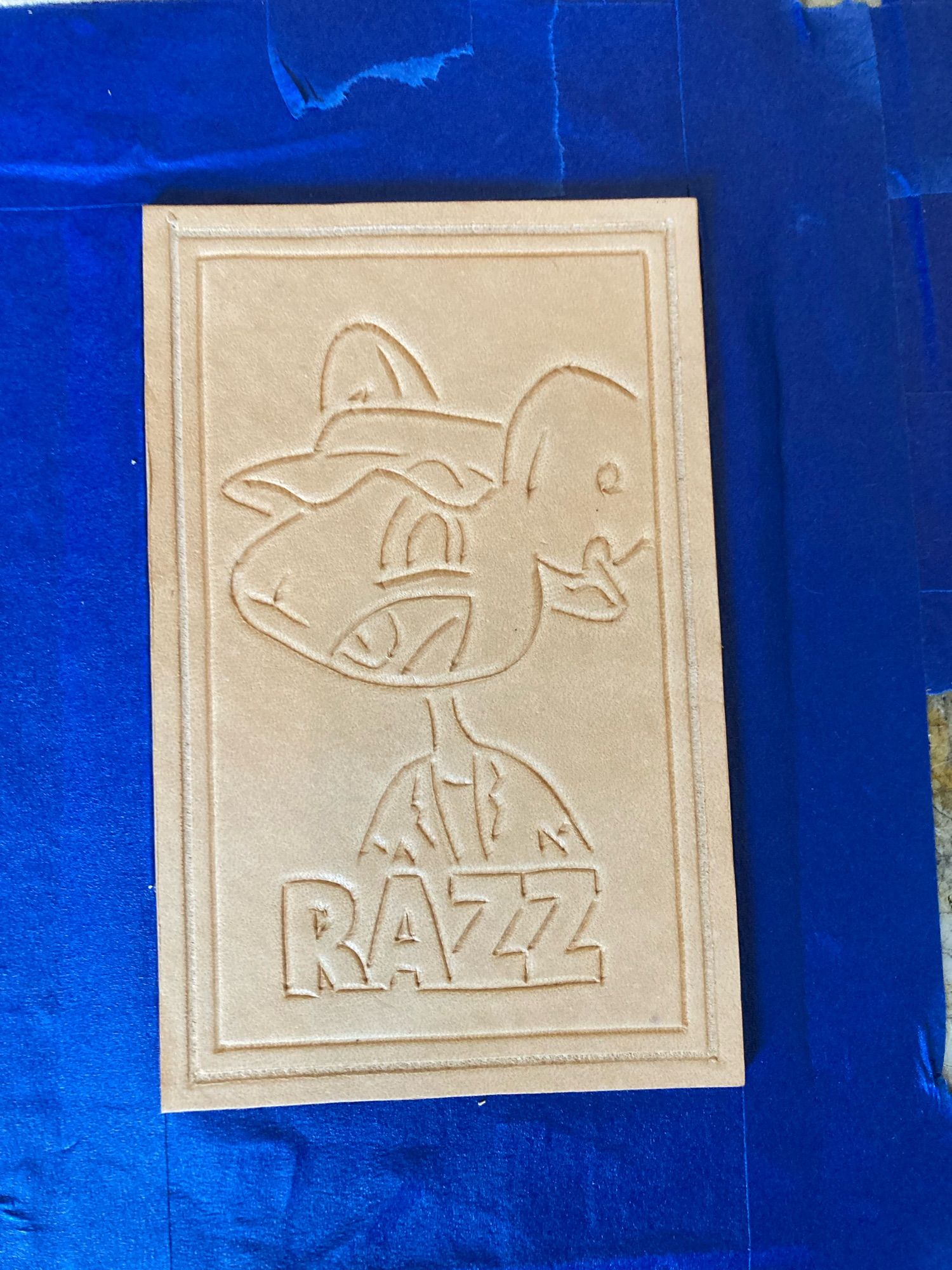 Unfinished leather patch of a rat with text “RAZZ”