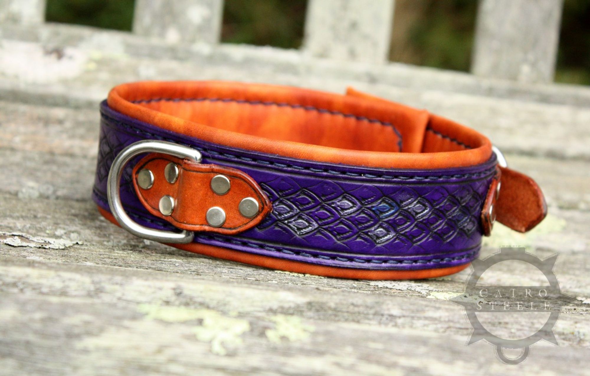 A handmade leather collar. It has a deep purple base strap with dragonscale tooling, with accent scales picked out in metallic blue and silver. The top straps and liner are saddle tan, and it has stainless steel hardware.