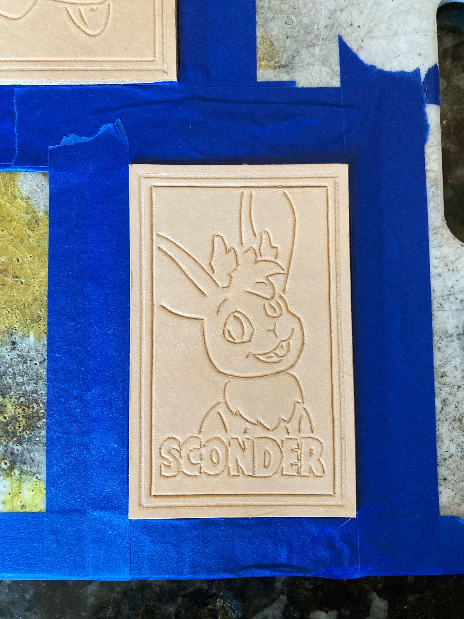 Unfinished leather patch of a jackalope with text “SCONDER”