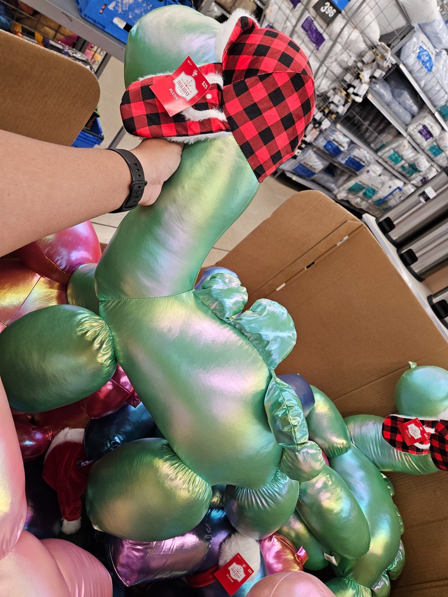 Green & pink iridescent loch ness monster shaped balloon animal stuffie. It's wearing a Buffalo paid ear flap hat