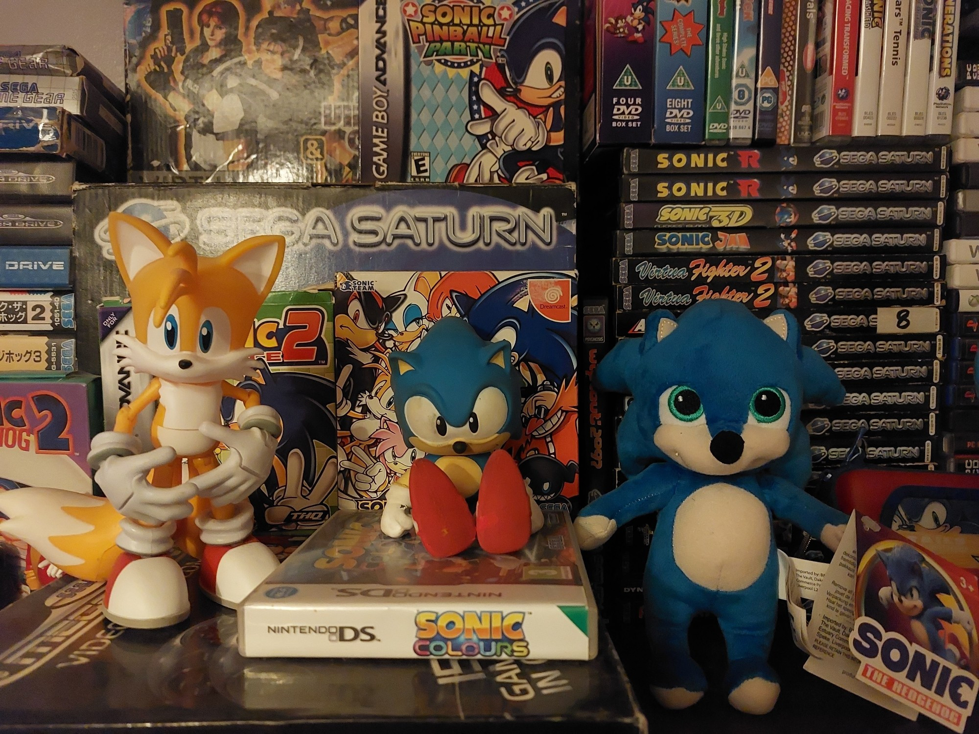 The top of my DVD cabinet where I keep the Sega Saturn games and boxed accessories, (most of)  the Sonic the Hedgehog games and a few Sonic toys, including a cursed movie plush.