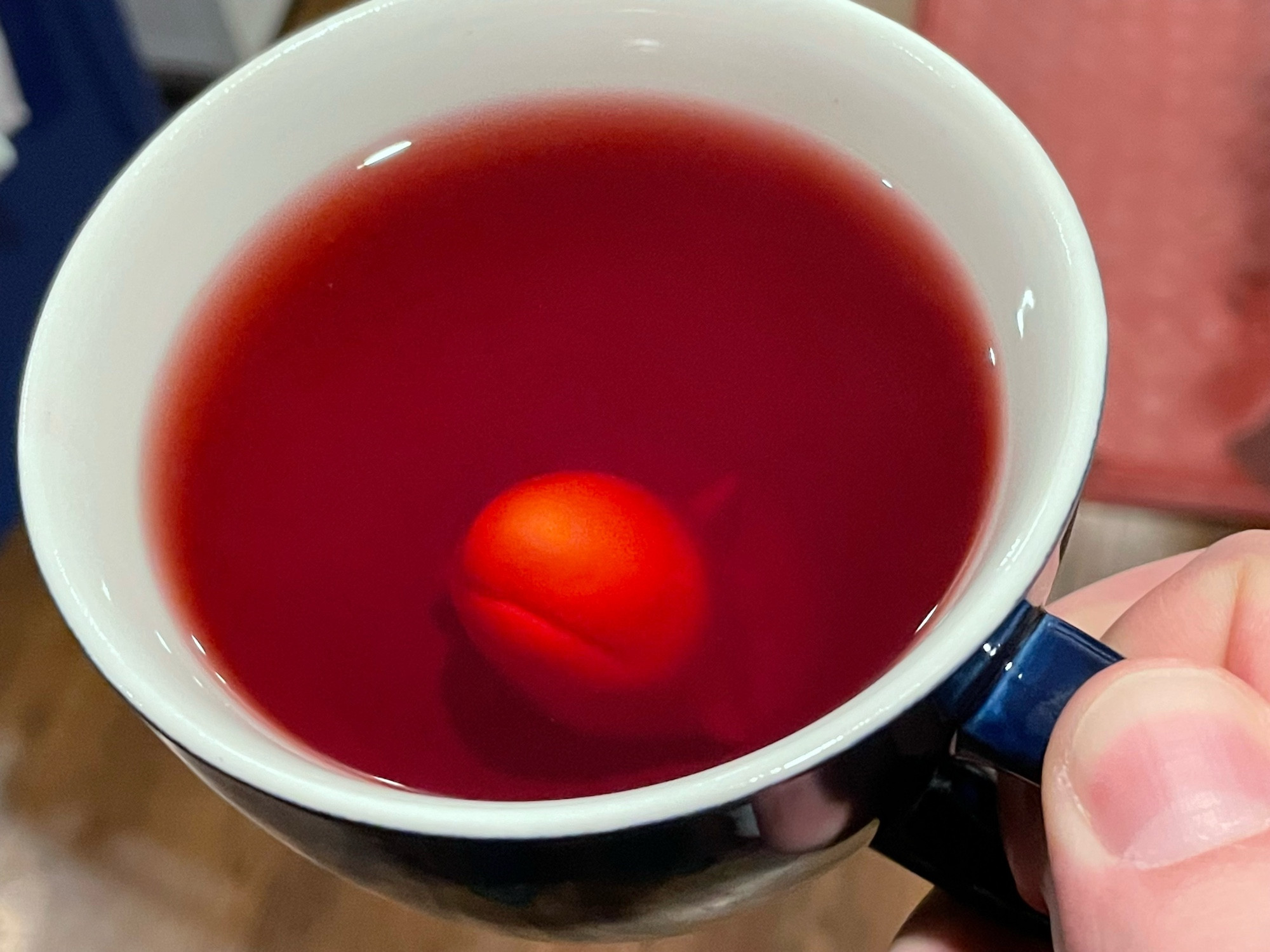 A mug of red-orange tea with a shark at the bottom