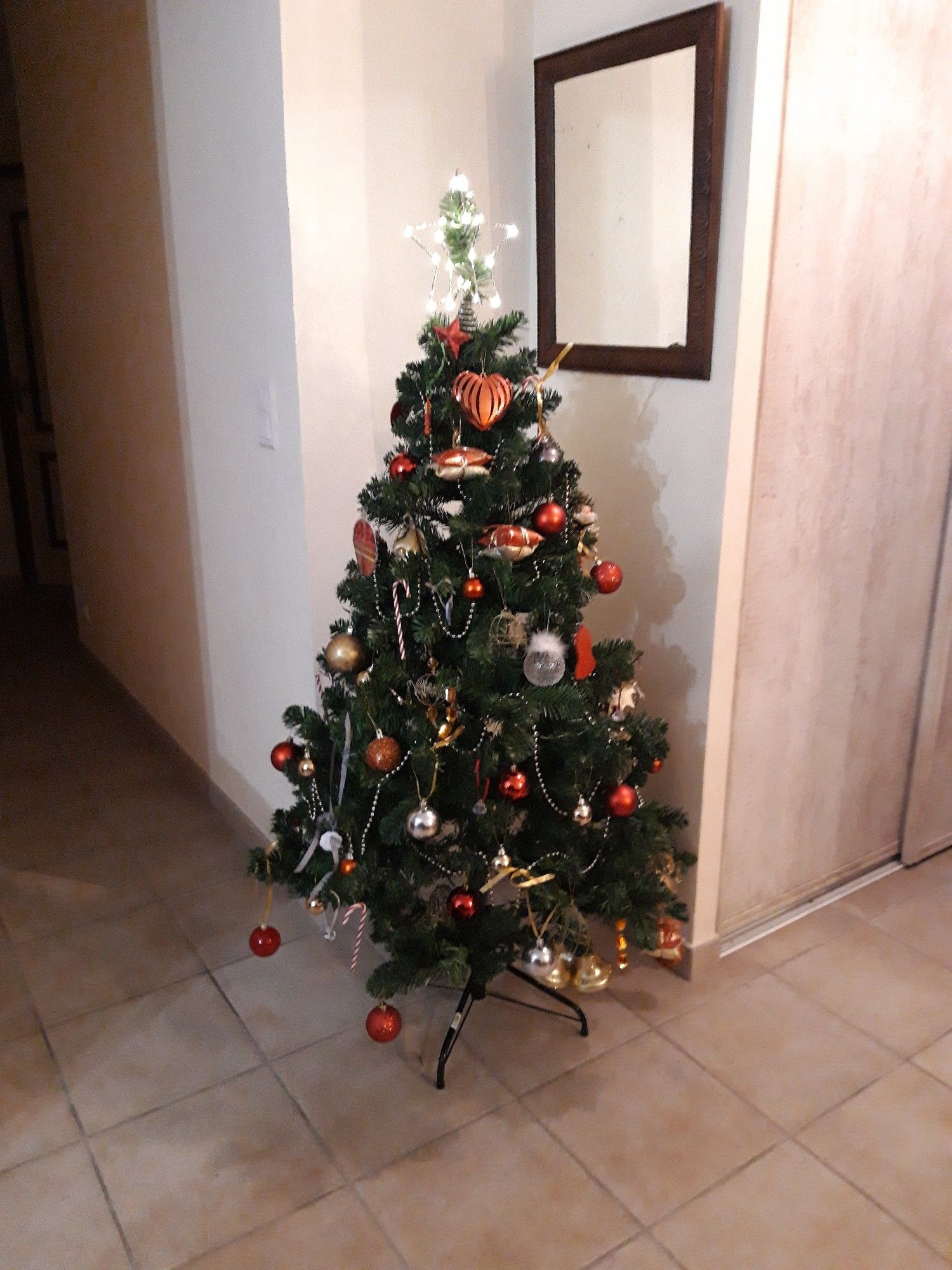 Sapin de Noël artificiel décoré principalement en rouge et doré