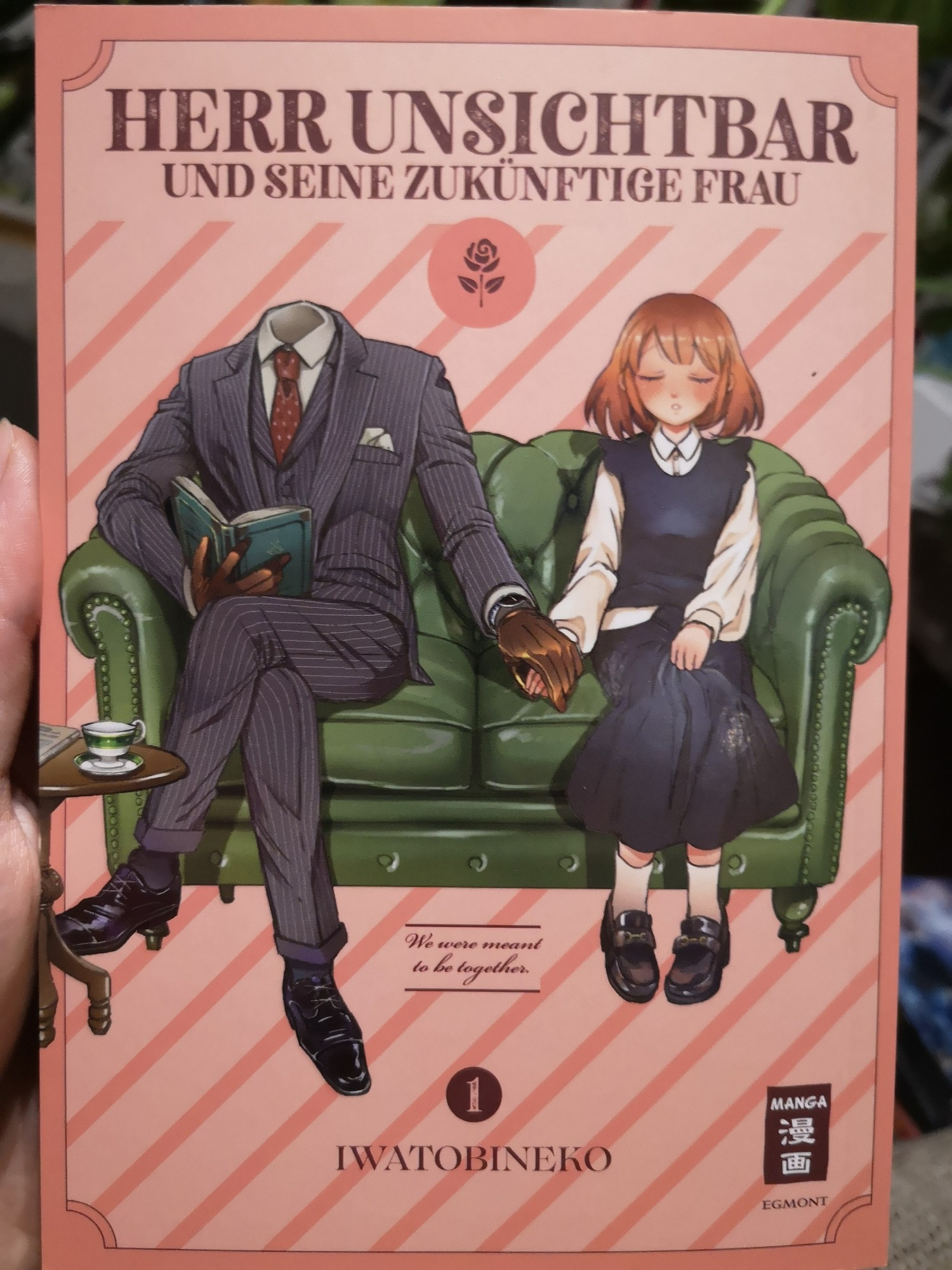 Manga "Herr Unsichtbar und seine zukünftige Frau". Auf dem Cover sitzen zwei Figuren auf einem Sofa und halten Händchen. Dabei ist bei dem einen nur die Kleidung zu sehen. Der Rest ist nicht sichtbar.