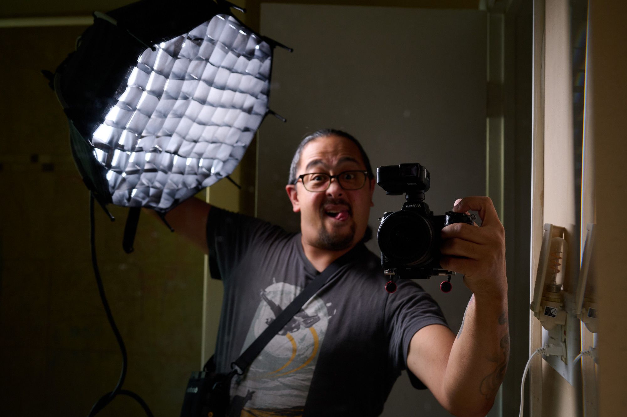 Mirror selfie with me holding a 12inch soft box to the side of my face with a Nikon Z6ii in my other hand.