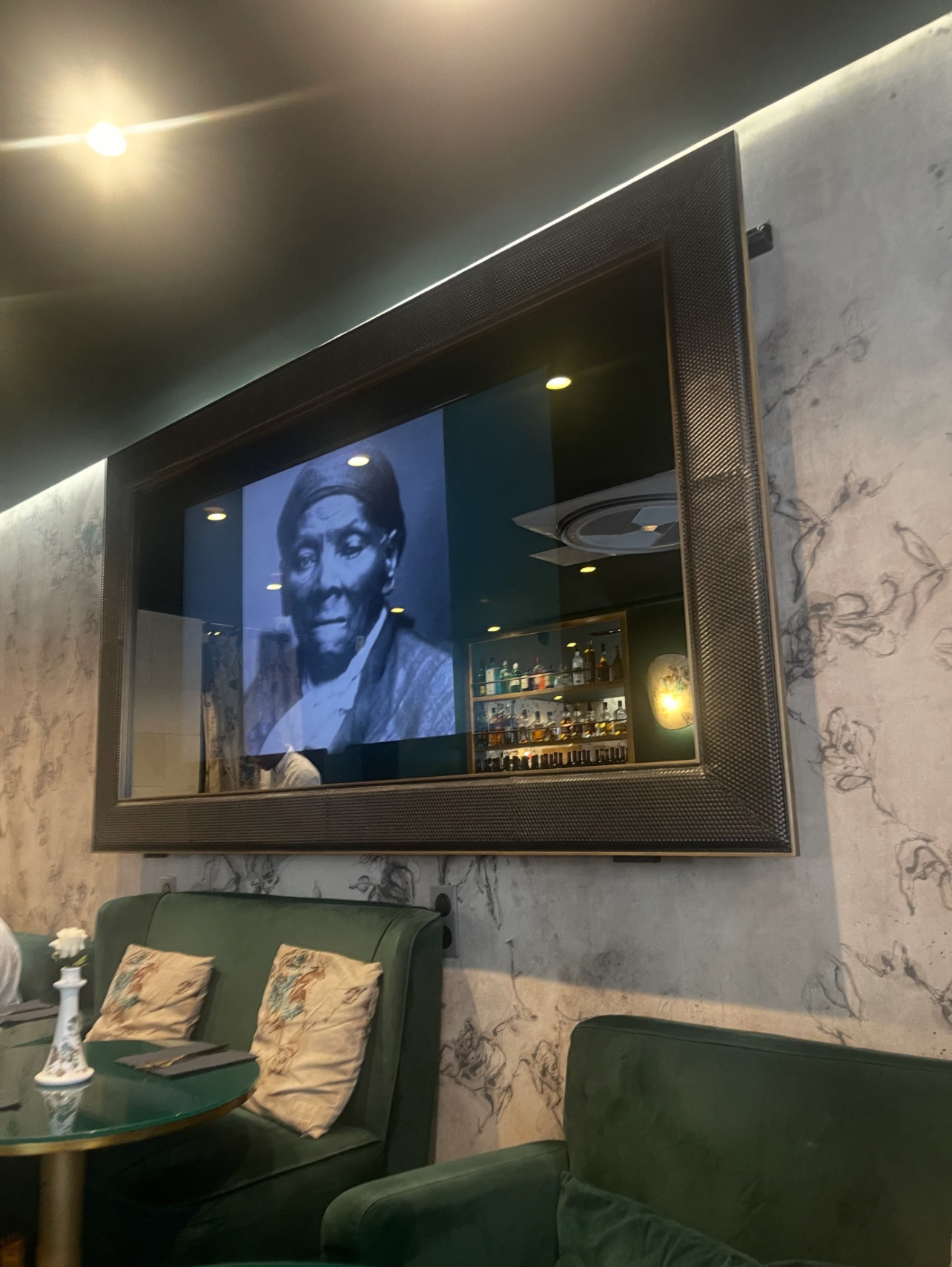 Harriet Tubman on a tv screen with green furniture below