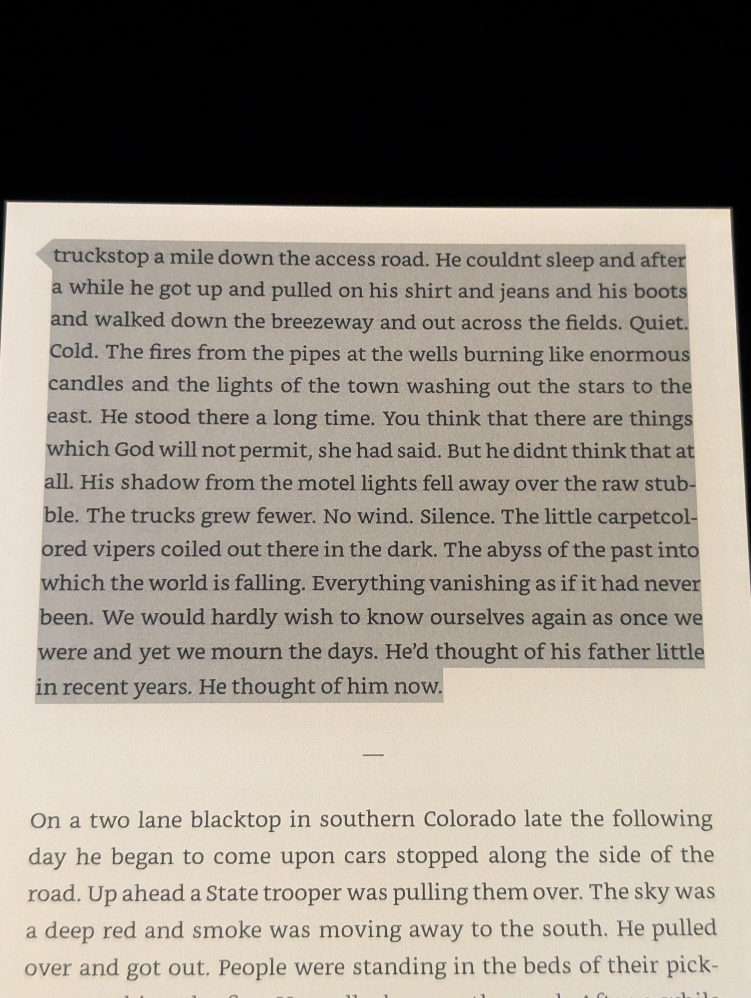 cormac mccarthy's the passenger (2002):

"...truckstop a mile down the access road. He couldnt sleep and after a while he got up and pulled on his shirt and jeans and his boots and walked down the breezeway and out across the fields. Quiet. Cold. The fires from the pipes at the wells burning like enormous candles and the lights of the town washing out the stars to the a east. He stood there a long time. You think that there are things which God will not permit, she had said. But he didnt think that at all. His shadow from the motel lights fell away over the raw stub ble. The trucks grew fewer. No wind. Silence. The little carpetcol ored vipers coiled out there in the dark. The abyss of the past into which the world is falling. Everything vanishing as if it had never been. We would hardly wish to know ourselves again as once we were and yet we mourn the days. He'd thought of his father little in recent years. He thought of him now."