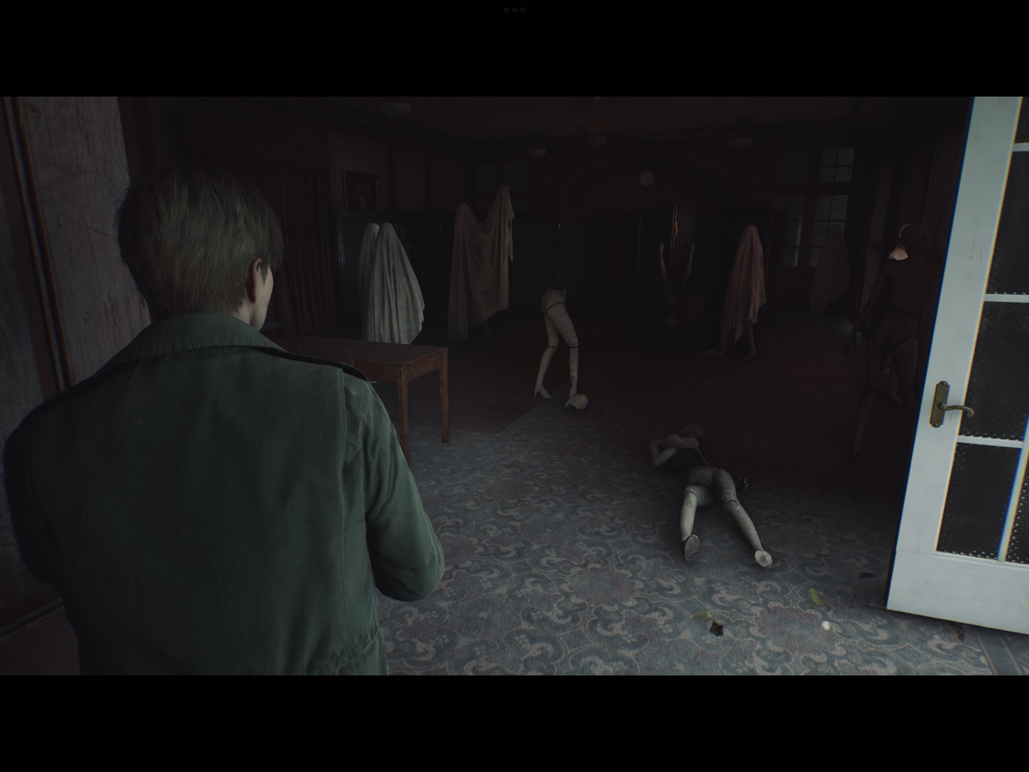 A screenshot from silent hill 2. A man is staring into a room with mannequins in it. Some mannequins are on the floor and others have cloth tripped over them. It’s very creepy.