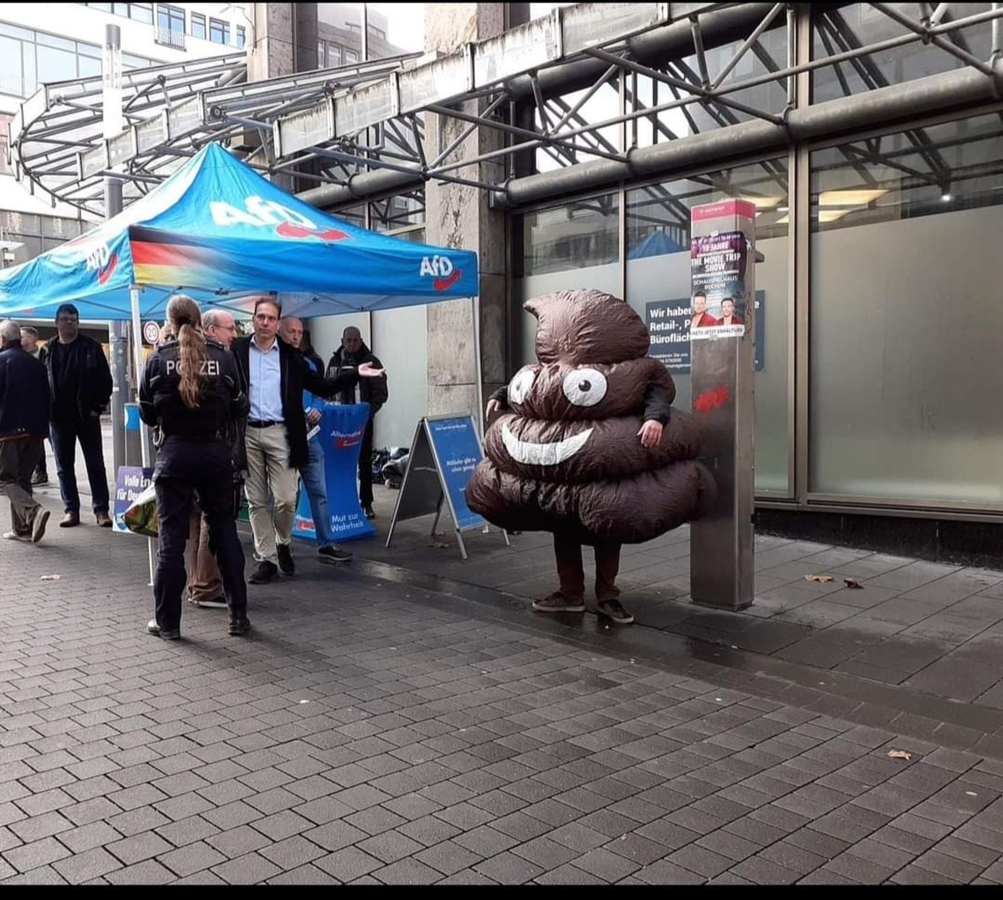 AfD Stand. Daneben eine Person in einem Scheiße Haufen-Kostüm.