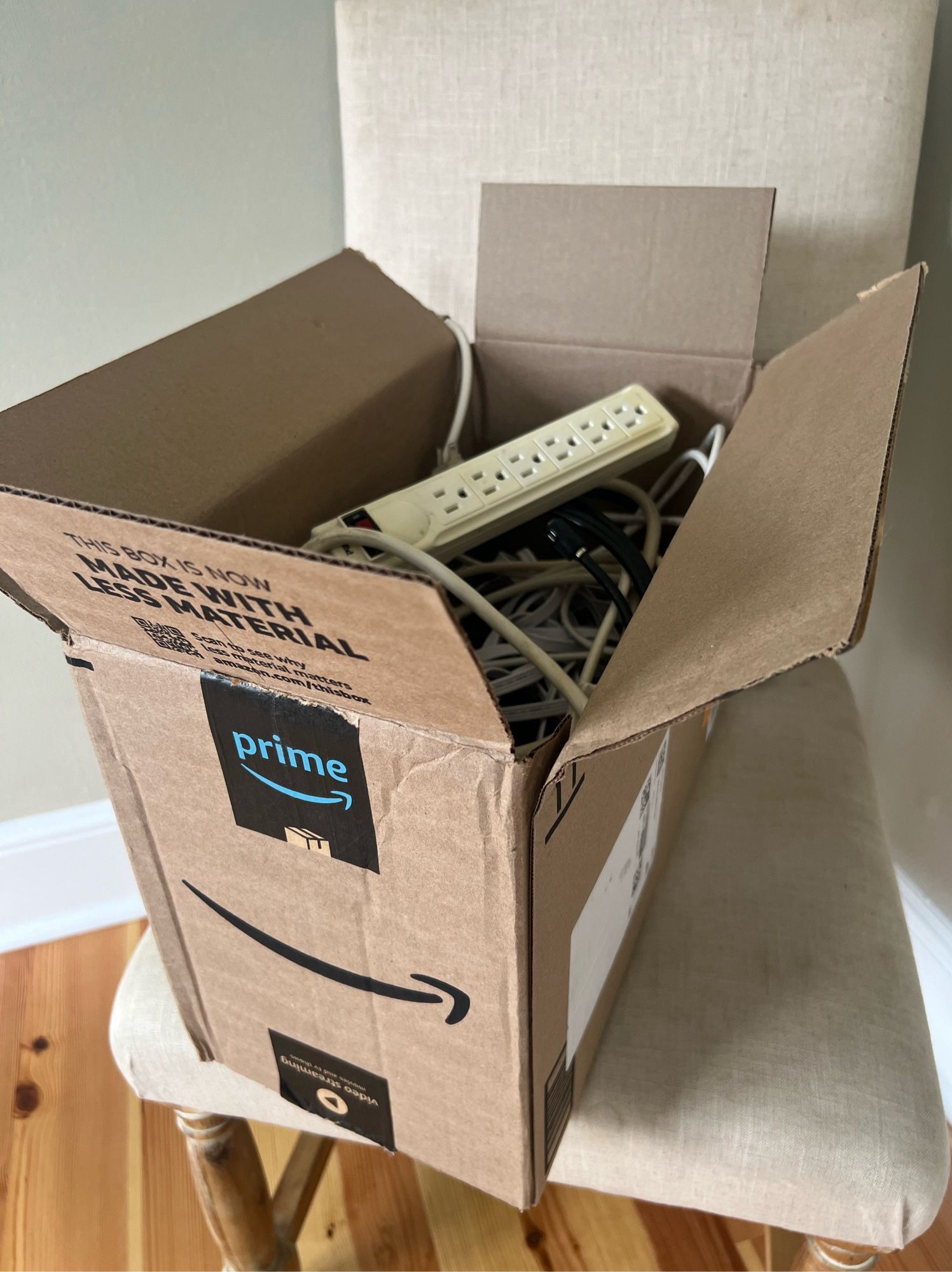 An Amazon box (narrower than it is deep) full of assorted cords and cables