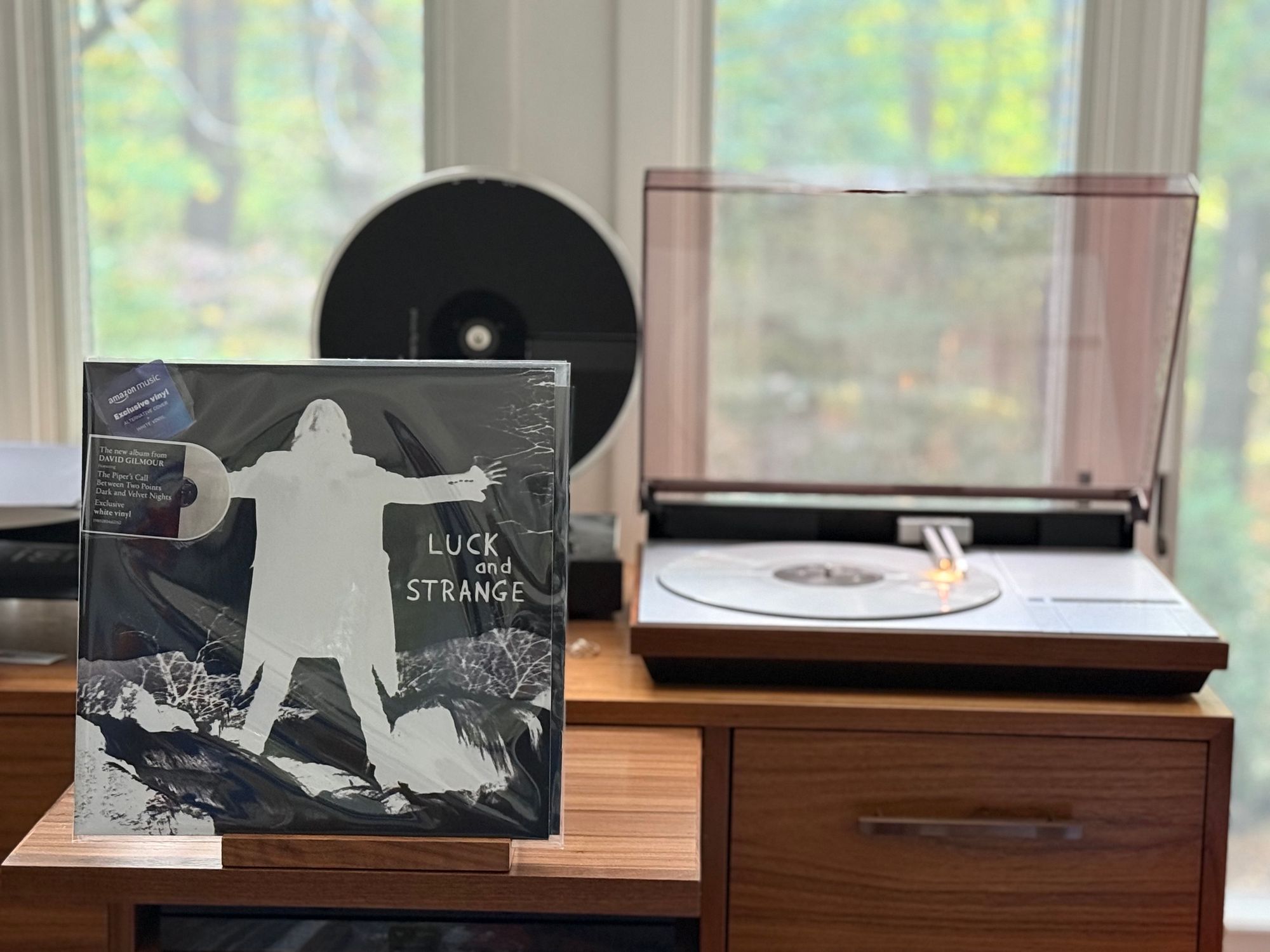 David Gilmour - Luck and Strange LP cover.

A negative reversal of Gilmour, a white cut-out against a rocky landscape, arms out, wearing what looks to be a long coat.

The white LP plays on a vintage, restored Bang & Olufsen Beogram 4000 linear-tracking turntable to the right.