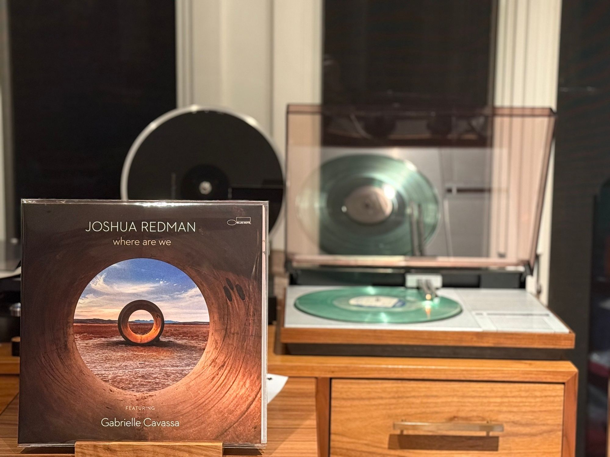 Joshua Redman - where are we LP cover.

A shot inside a large pipe, looking at another pipe, with a desert around. It almost looks like an eye, with the 2nd pipe being the pupil.

The clear LP plays on a vintage, restored Bang & Olufsen Beogram 4000 linear-tracking turntable to the right.