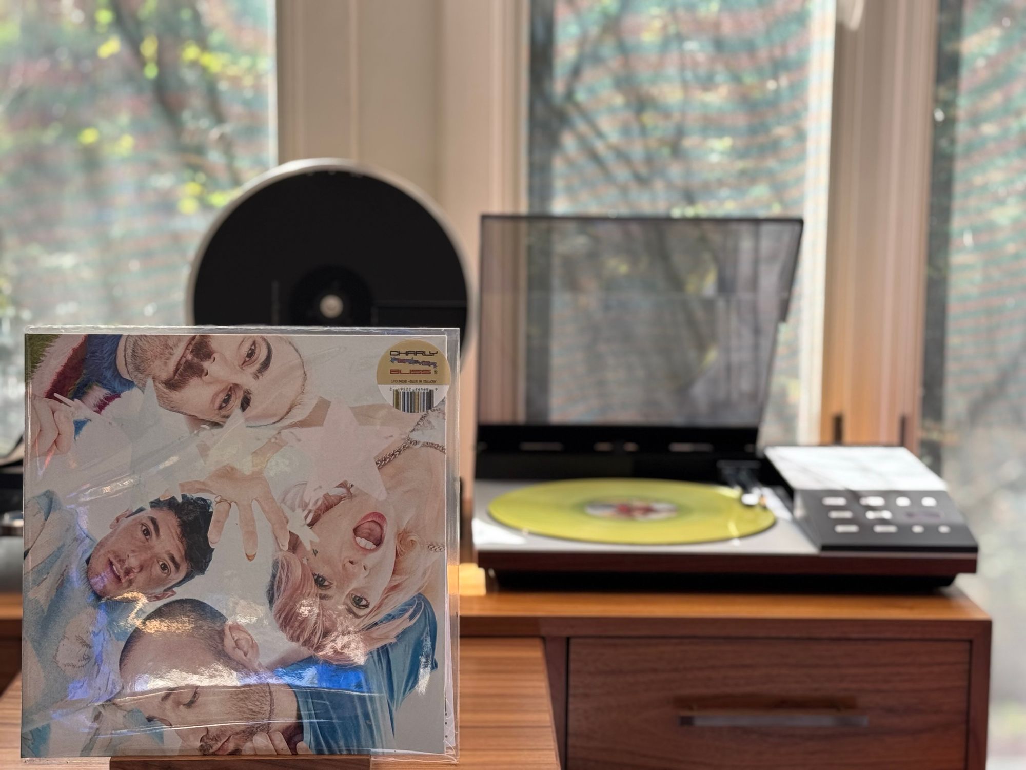 Charly Bliss - Forever LP cover.

The four band members, looking down at the camera, around the cover.

The “blue-in-yellow” LP plays on a vintage, restored Bang & Olufsen Beogram 8002 linear-tracking turntable to the right.