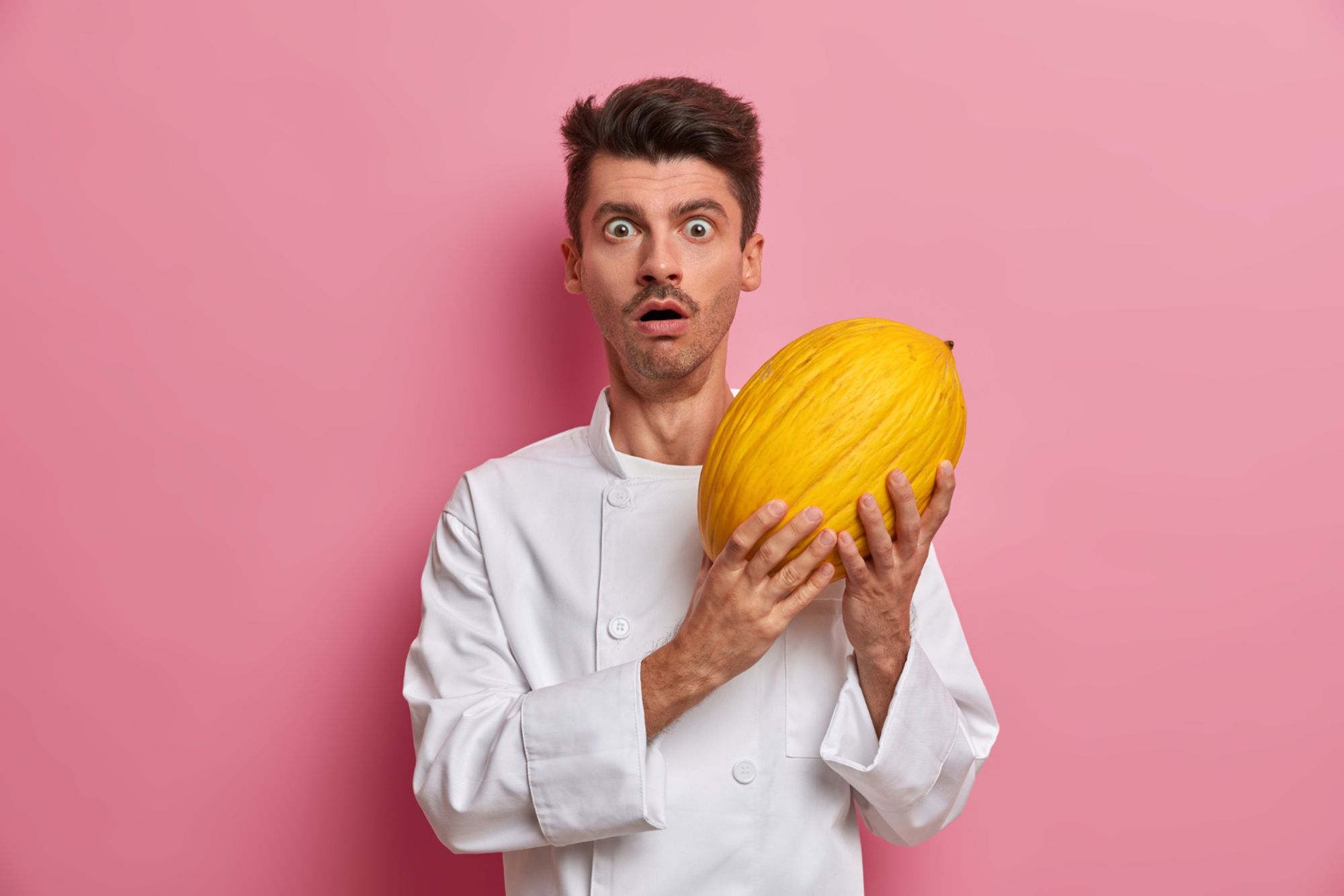 Cocinero sujetando un melón amarillo con cara de asombro