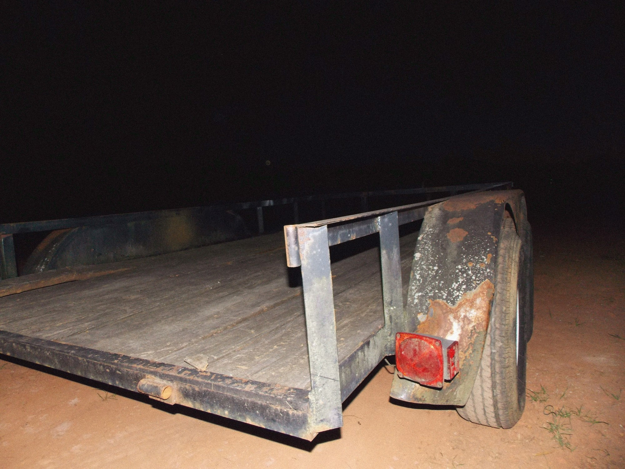 rusty flat bed trailer on dirt in the dark