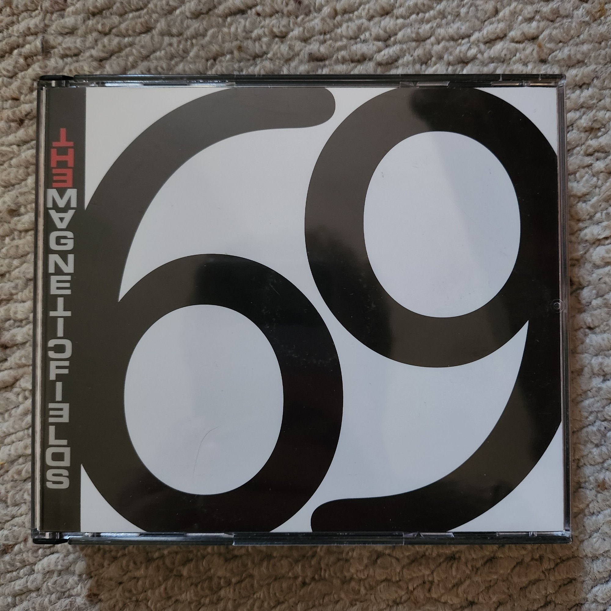 A double CD box of The Magnetic Fields' 69 Love Songs. The group's name is written down the left hand side, and the rest of the cover is taken up with the number 69 in black on a white background.