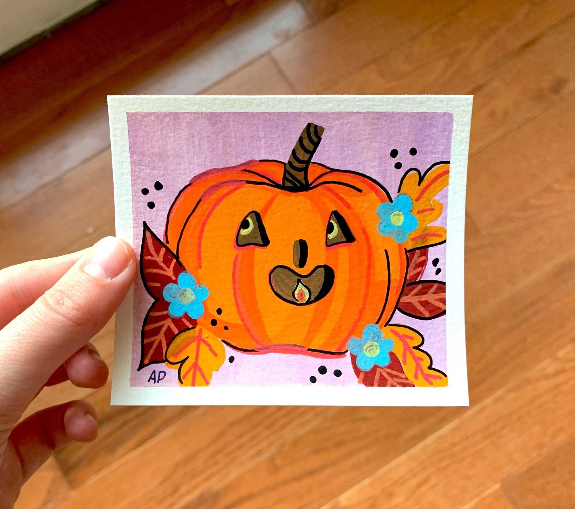 a painting of a happy Jack-o-lantern surrounded by fall leaves and flowers.