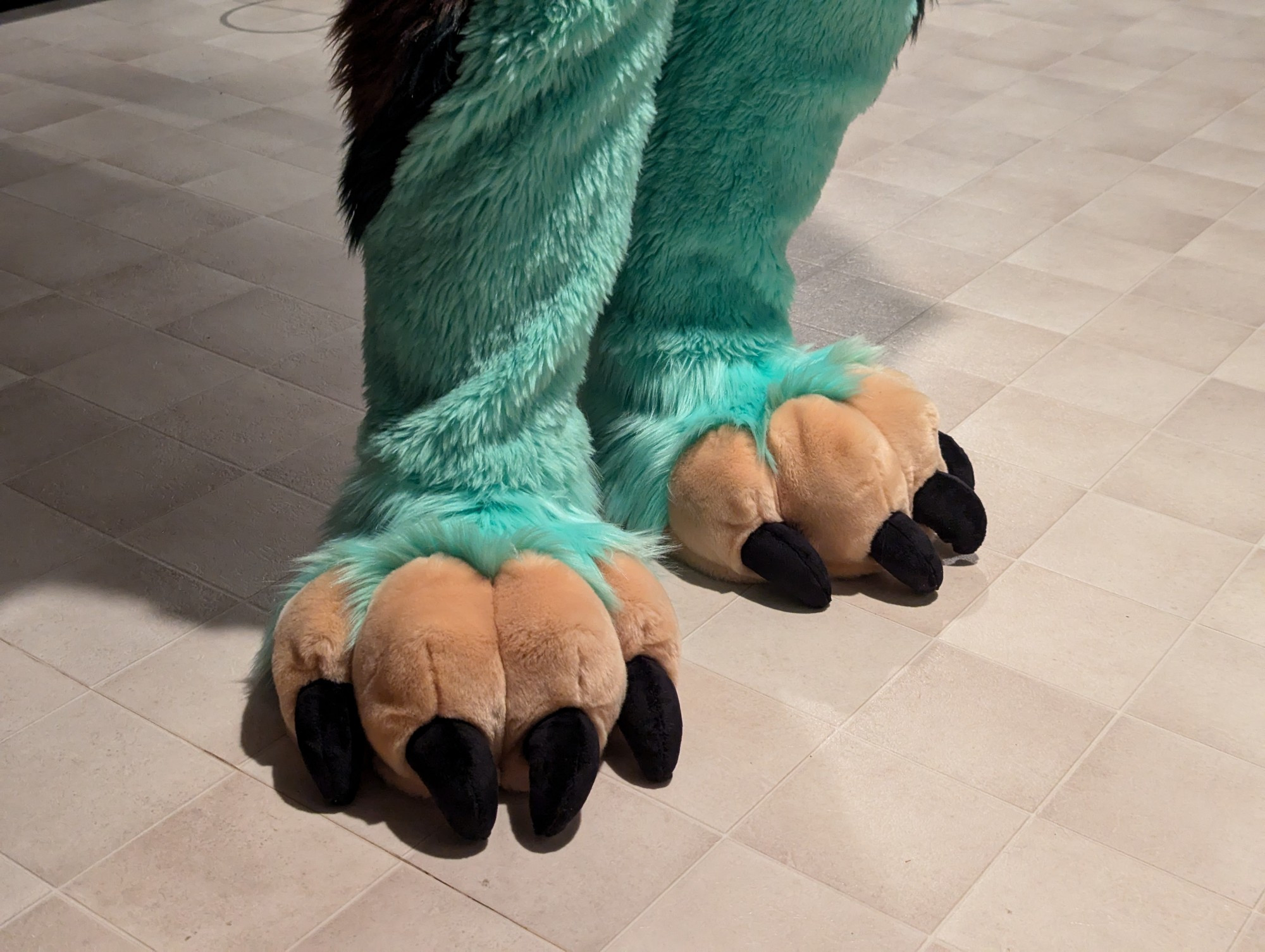 A photo of Ruvi's fursuit feetpaws while Coby is wearing them. The feet are attached to the suit leg so they won't separate.