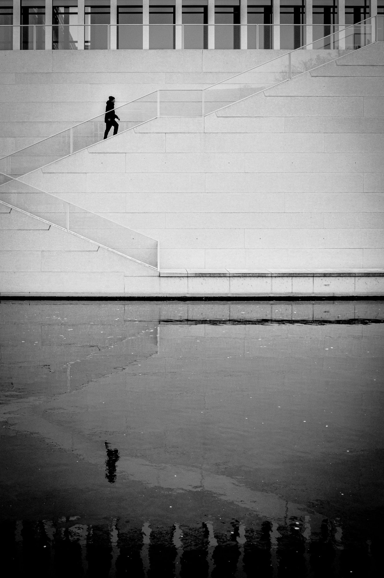 Streetphoto of Berlin - Black n White - person is stepping up stairs - reflection in river