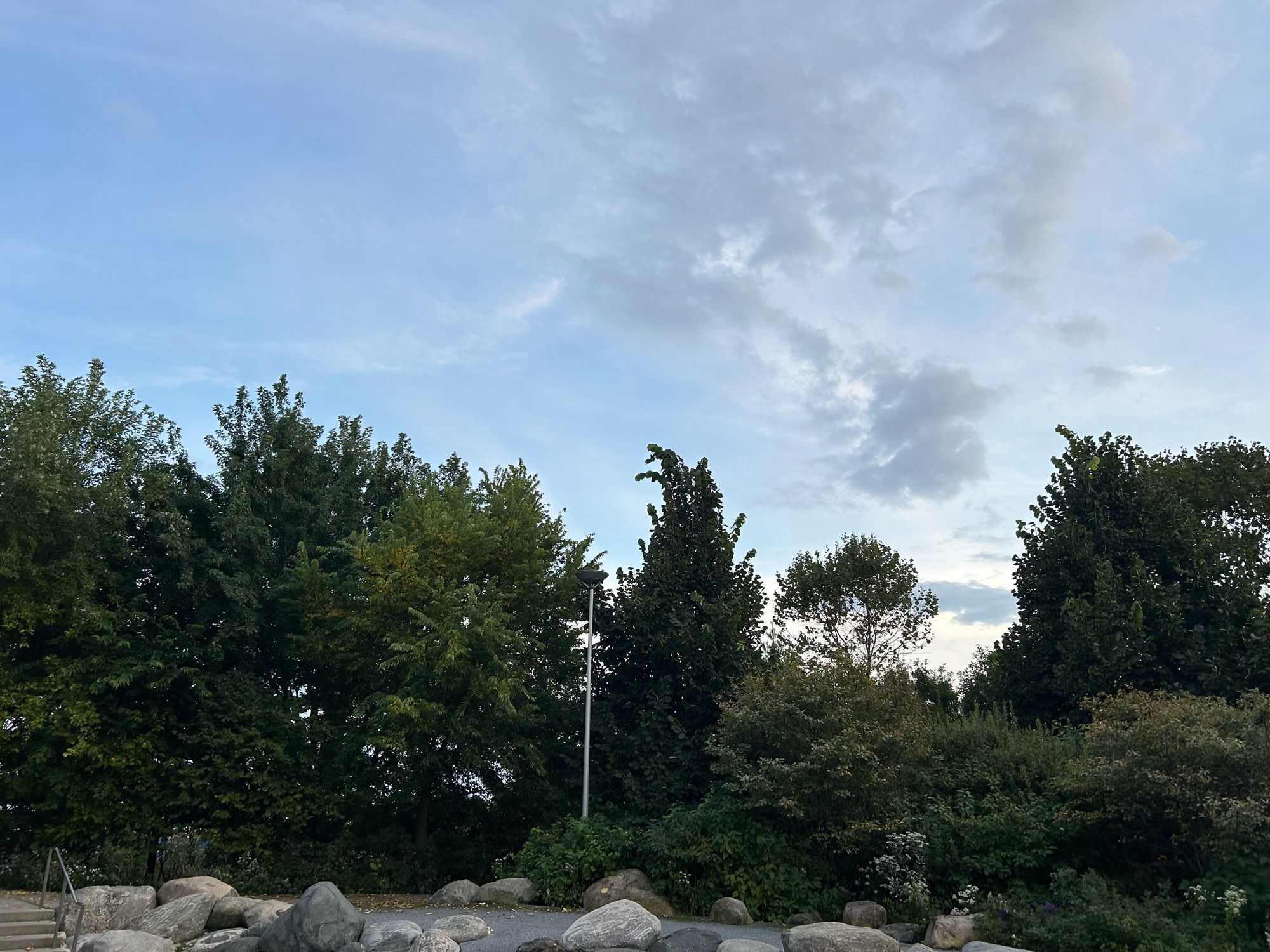 Evening view from the splash pad at Corktown Common, looking south and up at the sunset-lighted clouds