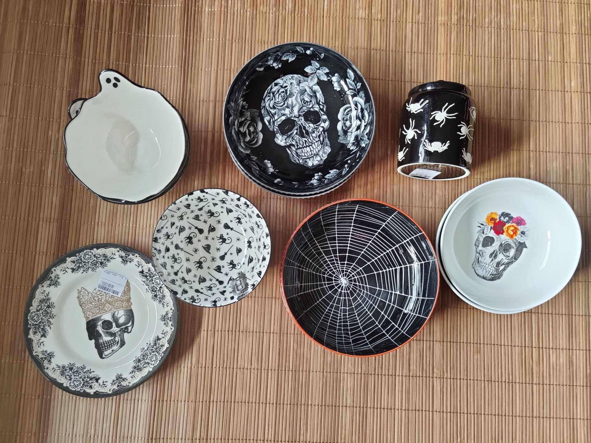 Three types of plates with a variety of designs, including skull designs (one has a golden crown, another has a flower crown and the third skull design is surrounded by flowers), spider webs, ghost, a cute withcy design (with broom, witch hat cats) and a storage jar with a spider design.