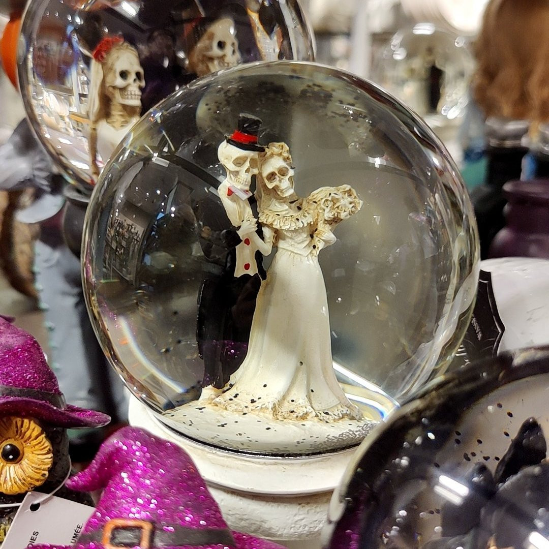 A Halloween-themed snow globe (with a skeleton wedding couple surrounded with other water globes and other trinkets.