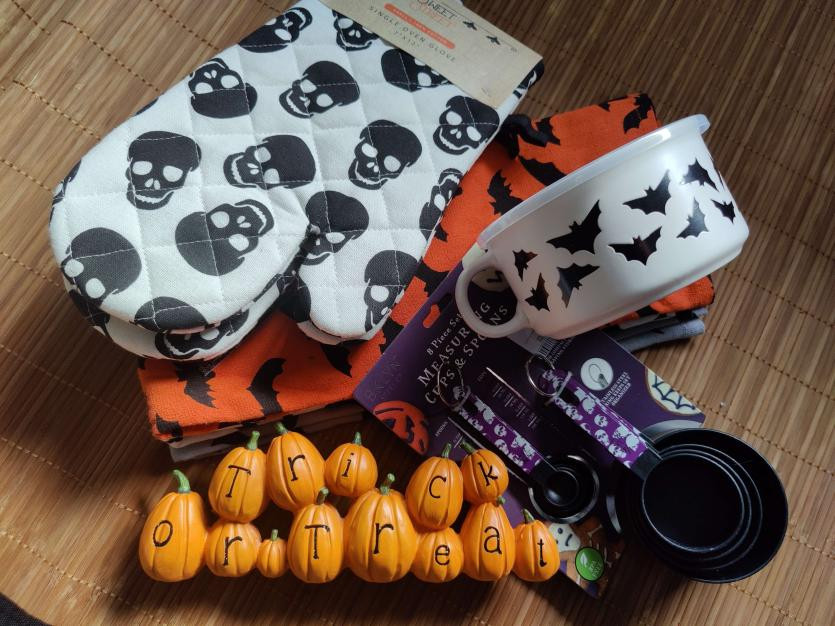 Oven mittens, a big mug for soups (in the end I bought several of them), a couple of tea towels in Halloween theme, measuring cups with Halloween design and a decorative statuette of pumpkins on a row and the text trick or treat.