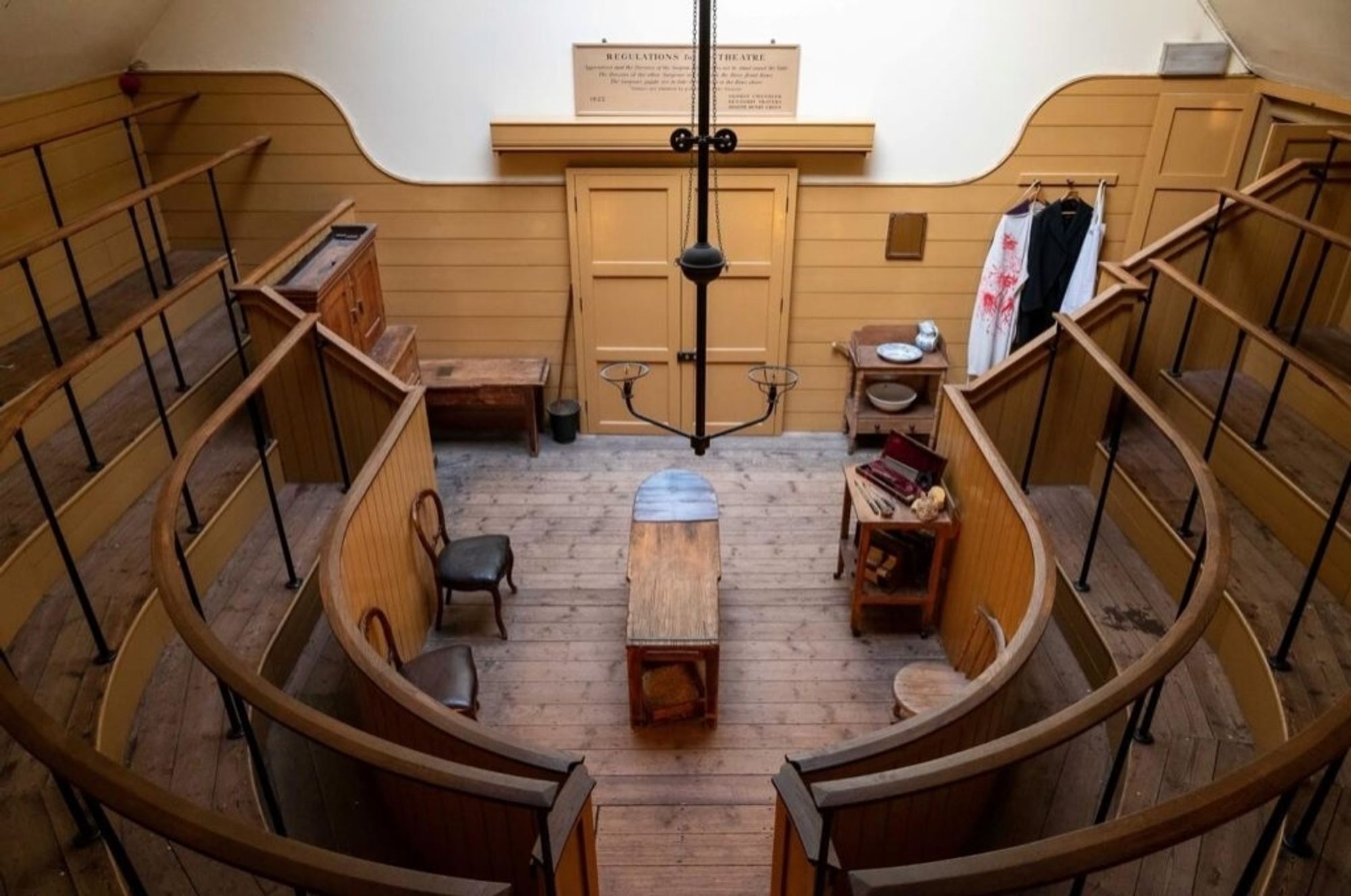 Victorian operating theater with a table in the middle and raised platforms surrounding it so that observers can see.