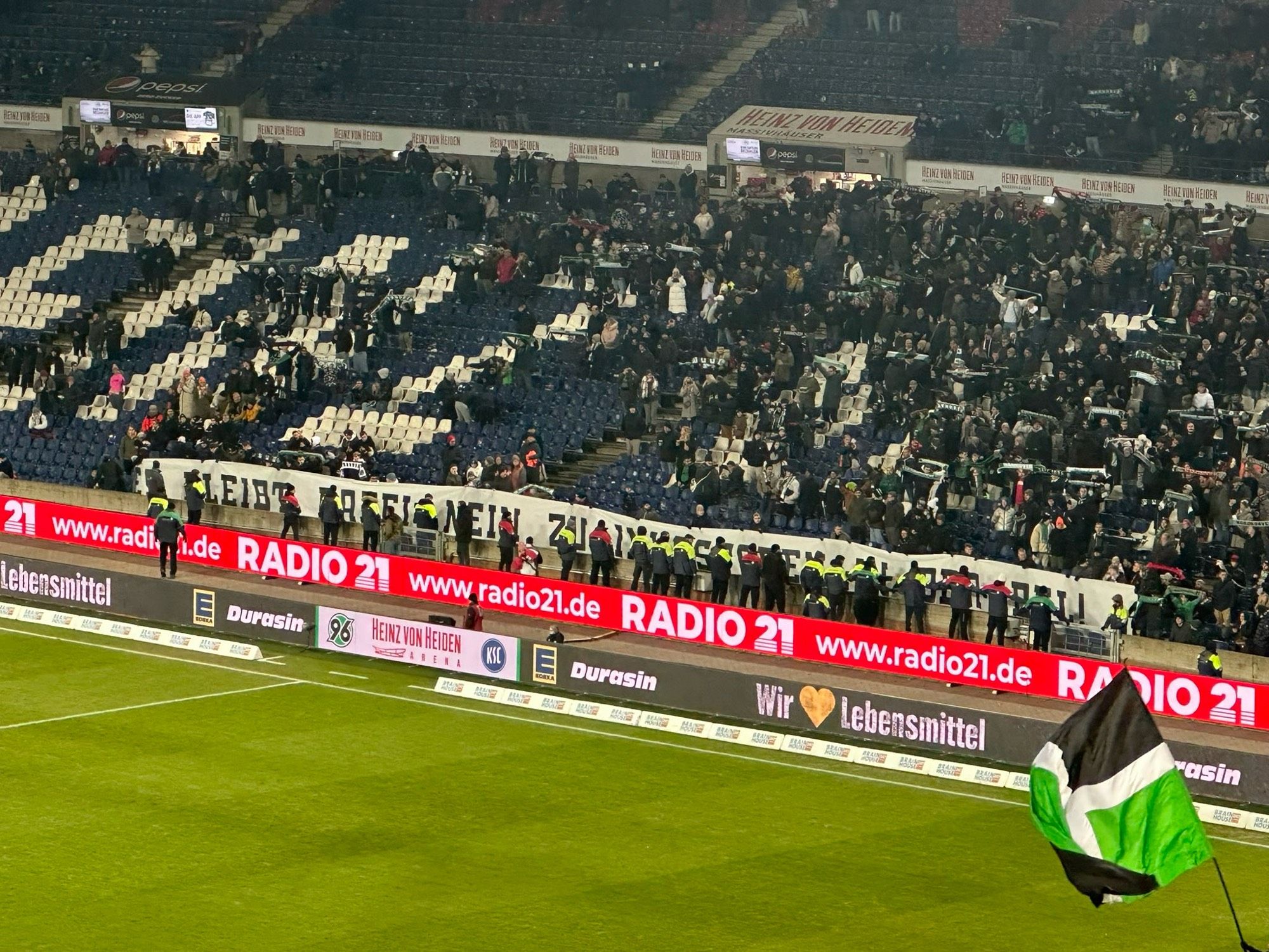 Stewards trying to prevent a banner against a potential investment into the German Football League (DFL) during Hannover’s 2. Bundesliga game vs. Karlsruhe to be shown by standing in front of it.